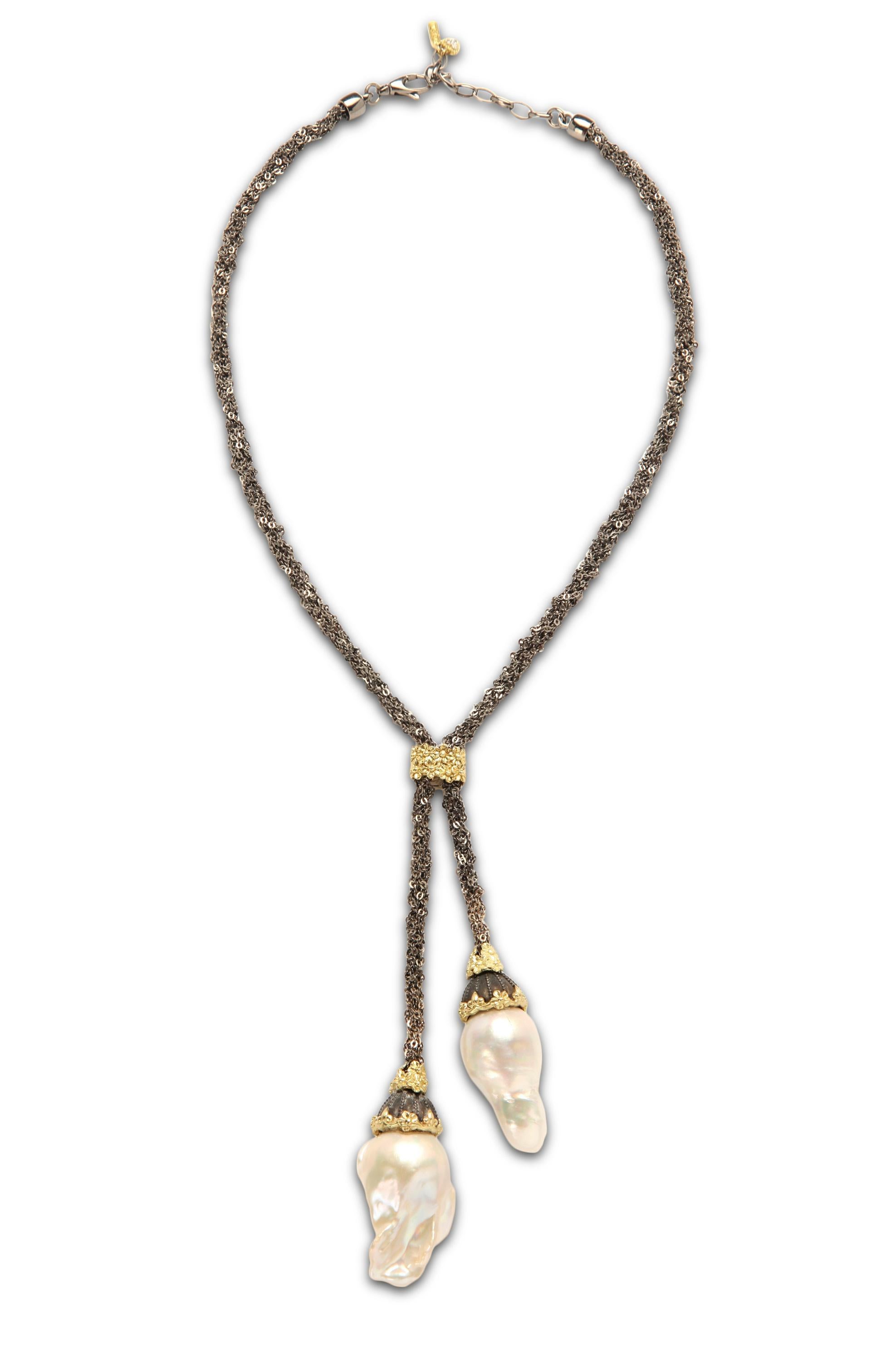 Darkened Aged Silver and 18K Gold Lariat Necklace with Two Baroque Pearl Drops by Stambolian

This unique necklaces features a gorgeous mesh type chain that is connected in the center by a gold floral design

The design leads to two drops with fresh