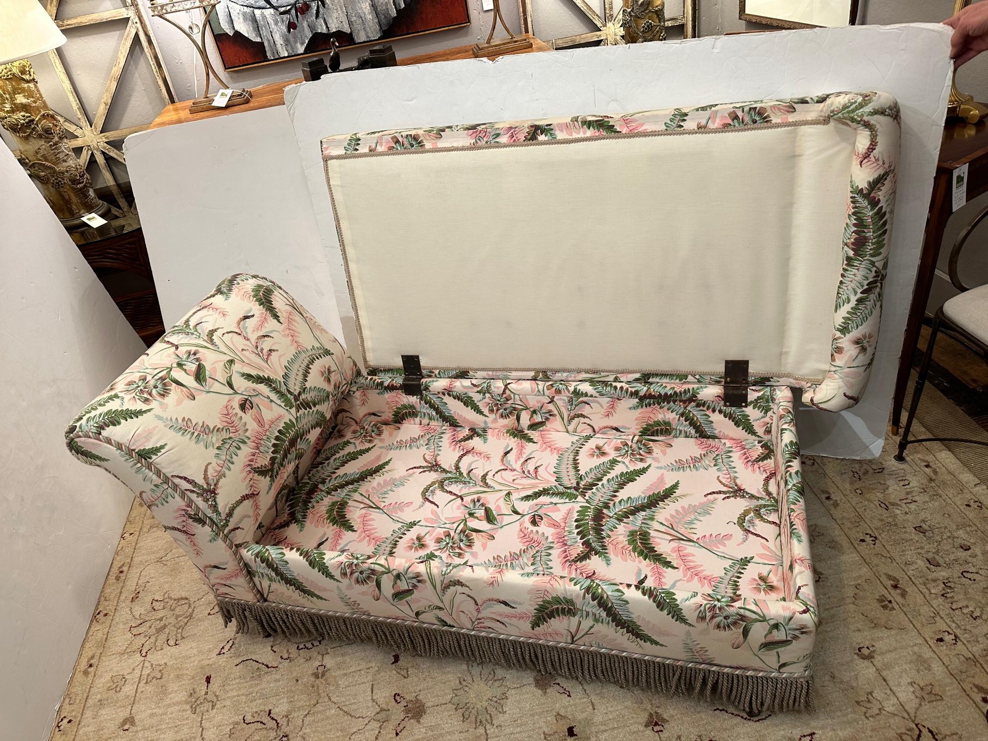 Darling small and comfy chaise longue upholstered in pretty tropical leaf motif cotton in pale pink, greens and cream, finished with bouillon fringe and a decorative rope. A surprising and helpful touch: the seat lifts up to reveal storage space