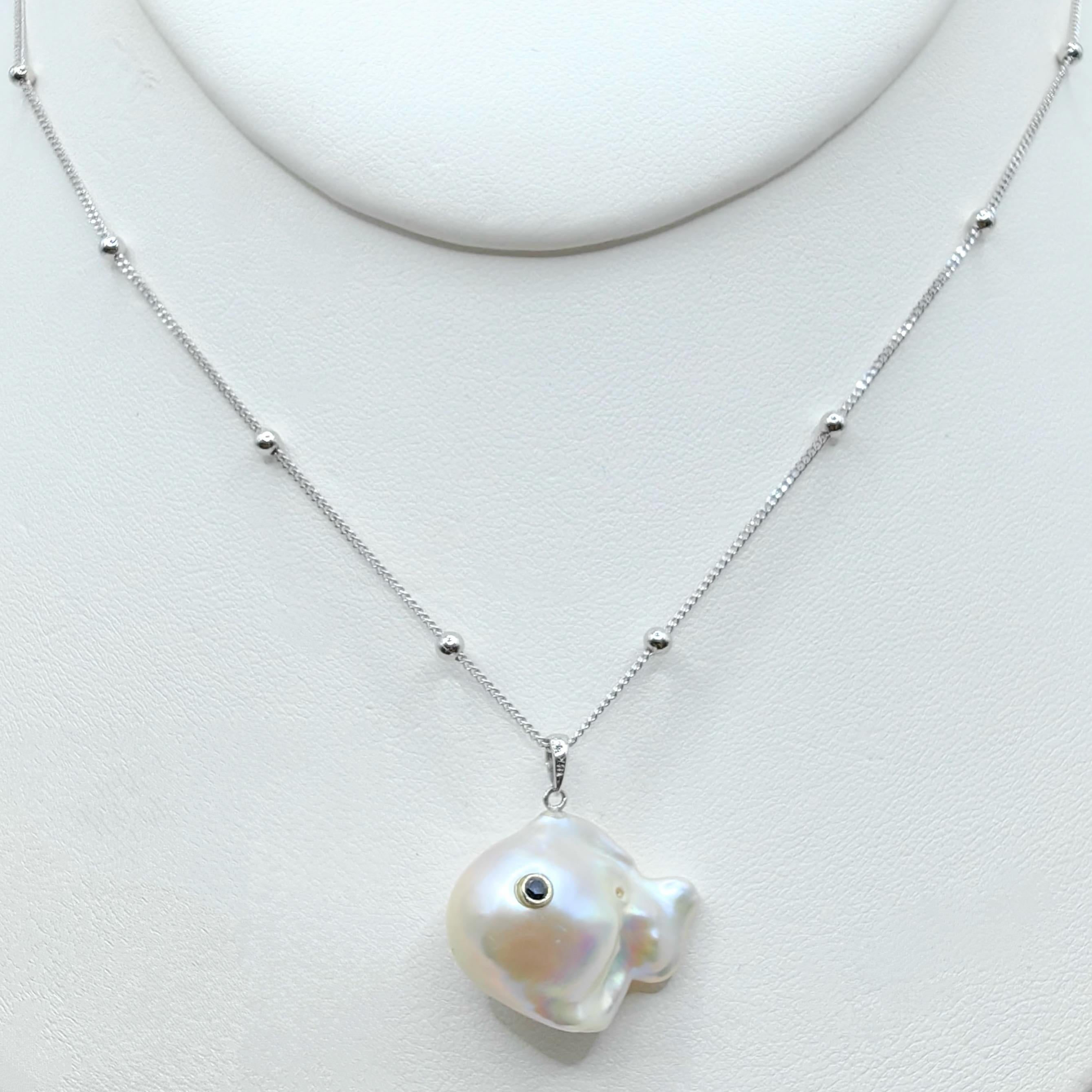 Dive into the whimsical depths of ocean-inspired charm with the captivating Darling Fish: Black Diamond Baroque Pearl Pendant in 18K White Gold. Crafted from a luminous freshwater baroque pearl, this playful pendant embodies the essence of marine