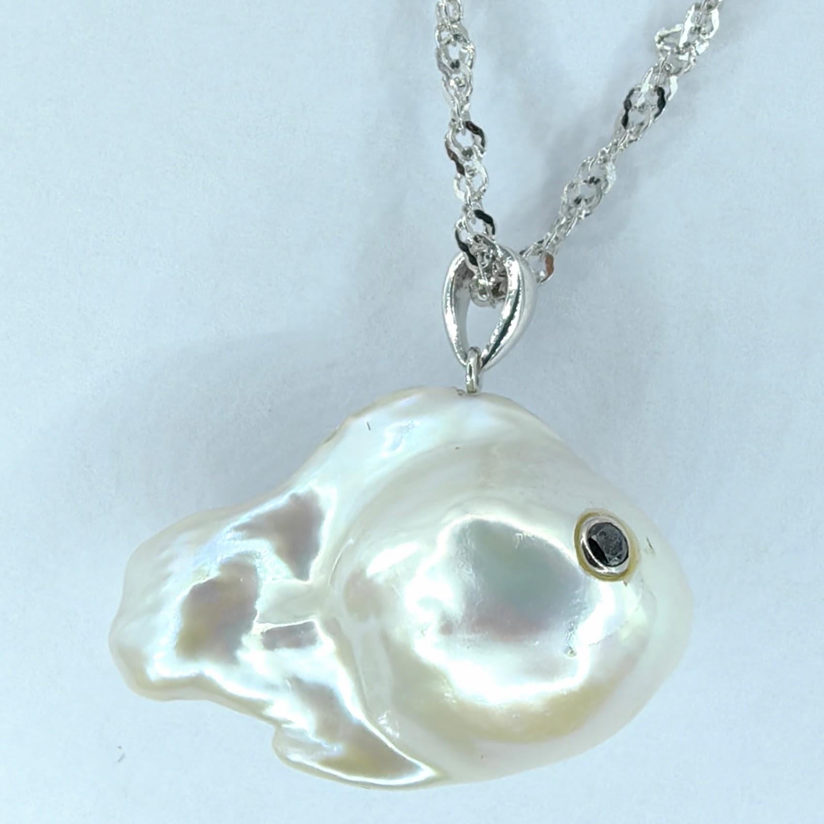 Dive into the whimsical depths of ocean-inspired charm with the captivating Darling Fish: Black Diamond Baroque Pearl Pendant in 18K White Gold. Crafted from a luminous freshwater baroque pearl, this playful pendant embodies the essence of marine
