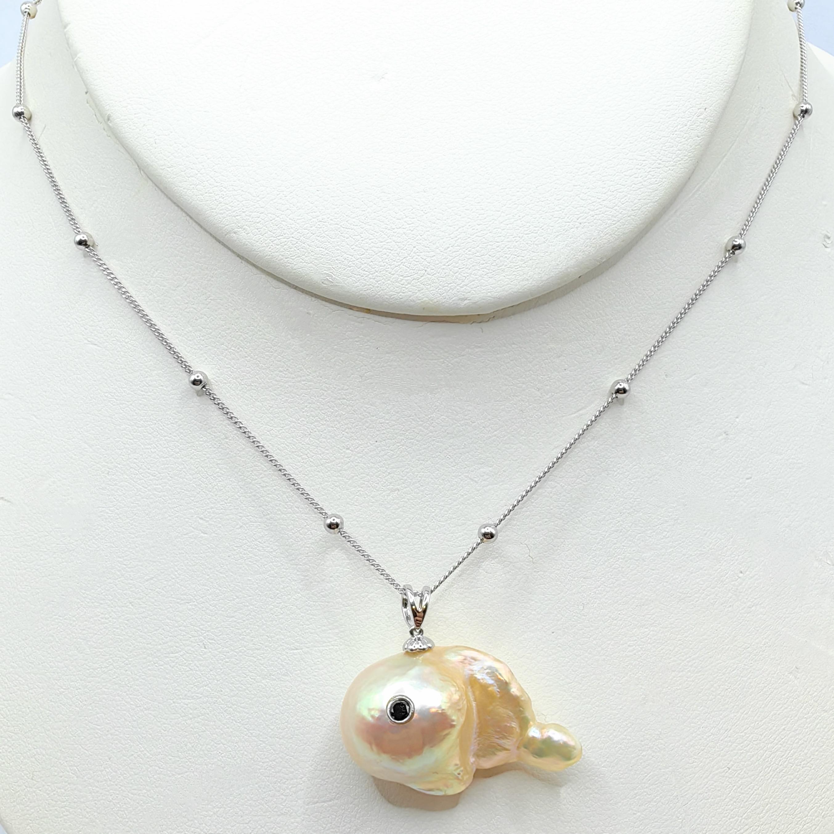 Dive into the whimsical depths of ocean-inspired charm with the captivating Darling Fish: Black Diamond Golden Baroque Pearl Pendant in 18K White Gold. Crafted from a luminous freshwater golden pink baroque pearl, this playful pendant embodies the