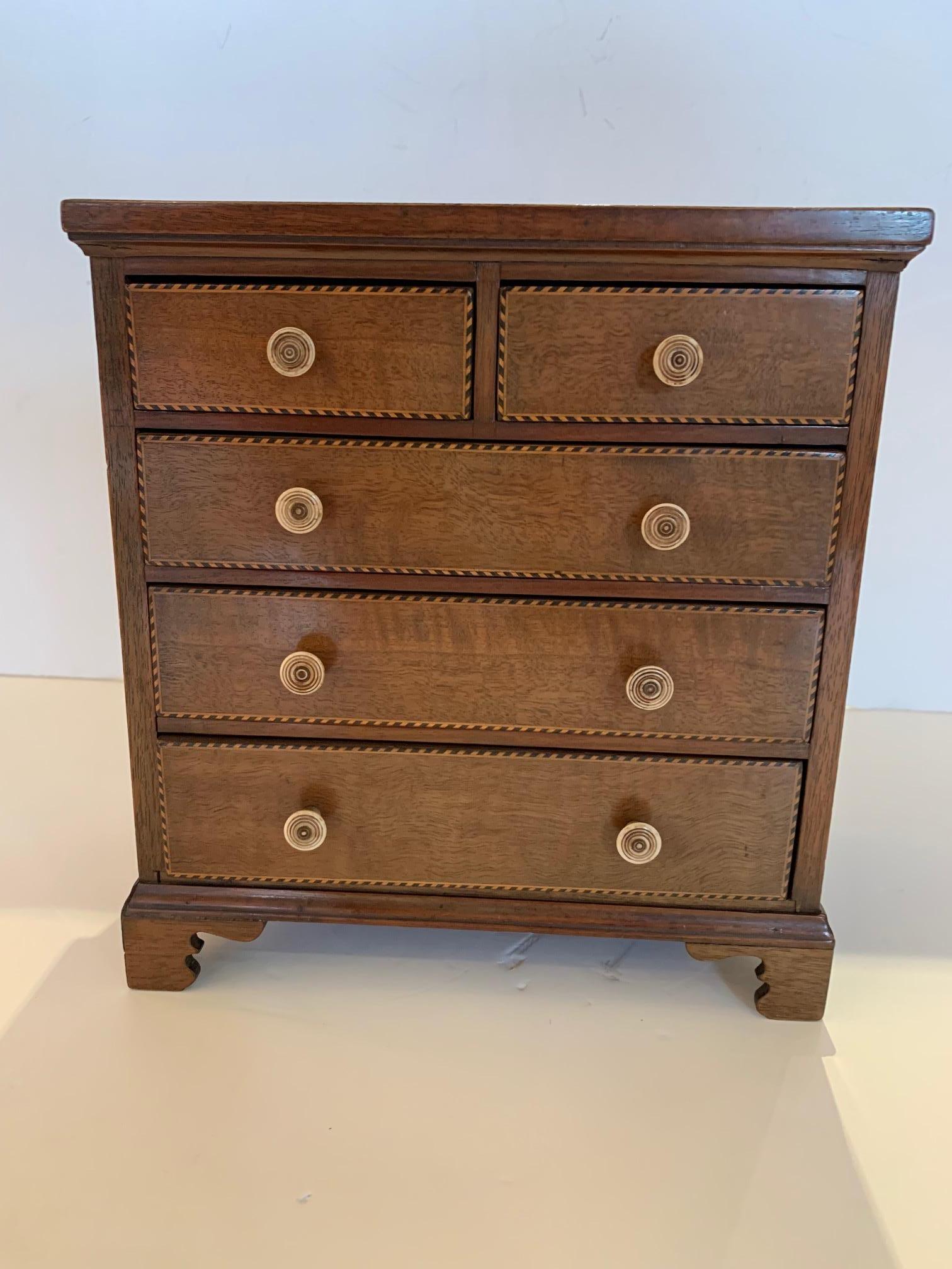 A beautifully made 19th century walnut inlay treasure box that's a miniature chest of drawers having 5 dovetailed drawers with bone hardware. The top has a lovely inlaid seashell adorning it.