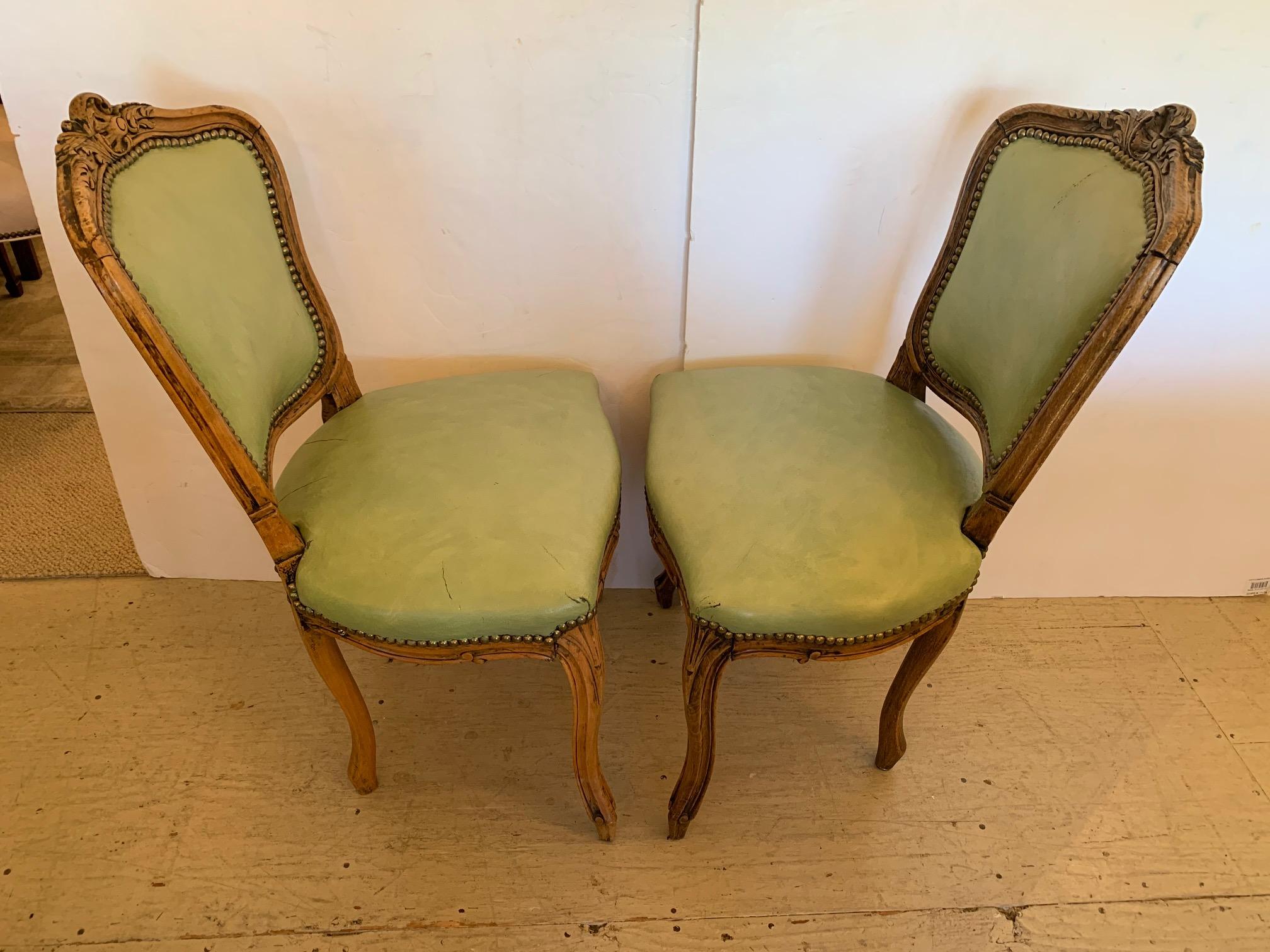 A diminutive pair of antique classic French carved light colored walnut side chairs upholstered in a delightful shade of faded lime green leather with brass nailheads.
Measures: Seat: 14” D x 17” H.