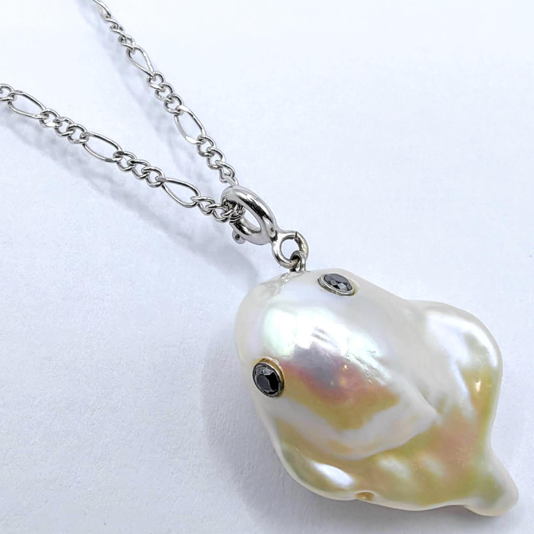 Enthüllen Sie den bezaubernden Darling Phantom: Black Diamond Baroque Pearl Ghost Charm aus 18 Karat Weißgold, der den Geist eines schelmischen fliegenden Geistes heraufbeschwört. Diese weiße Süßwasser-Zuchtperle im Barockstil mit einem Gewicht von