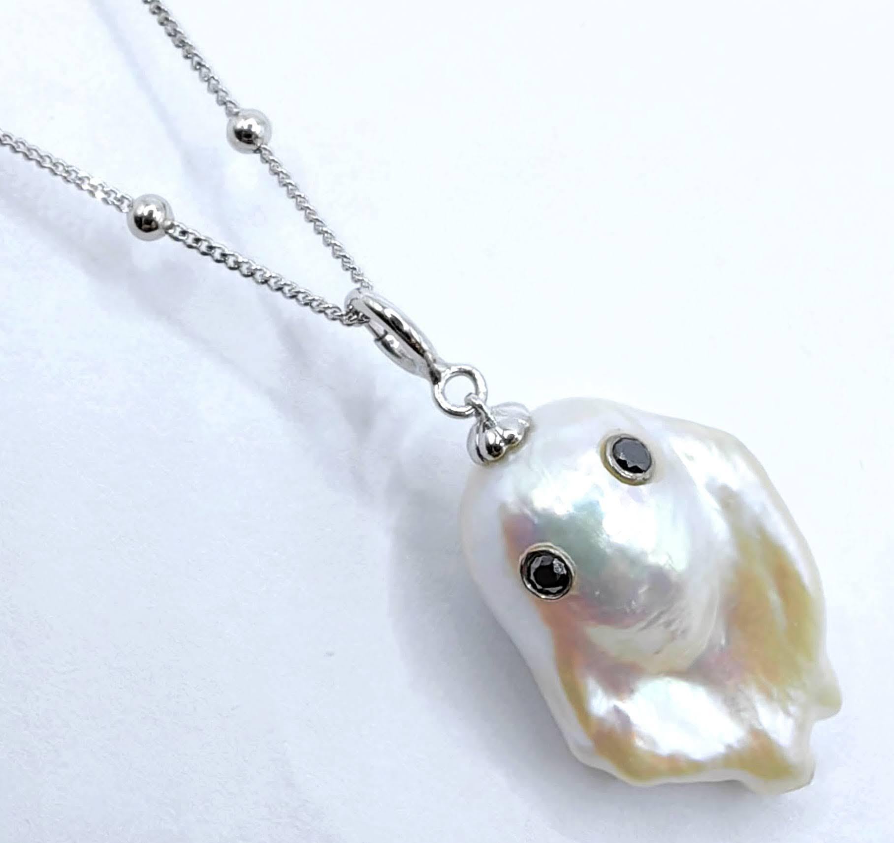 Unveil the enchanting Darling Phantom: a whimsical marvel featuring a Black Diamond accented Baroque Pearl set in 18K White Gold, evoking the spirit of a friendly ghost. This adorable piece, with a pendant length of approximately 1.35 inches