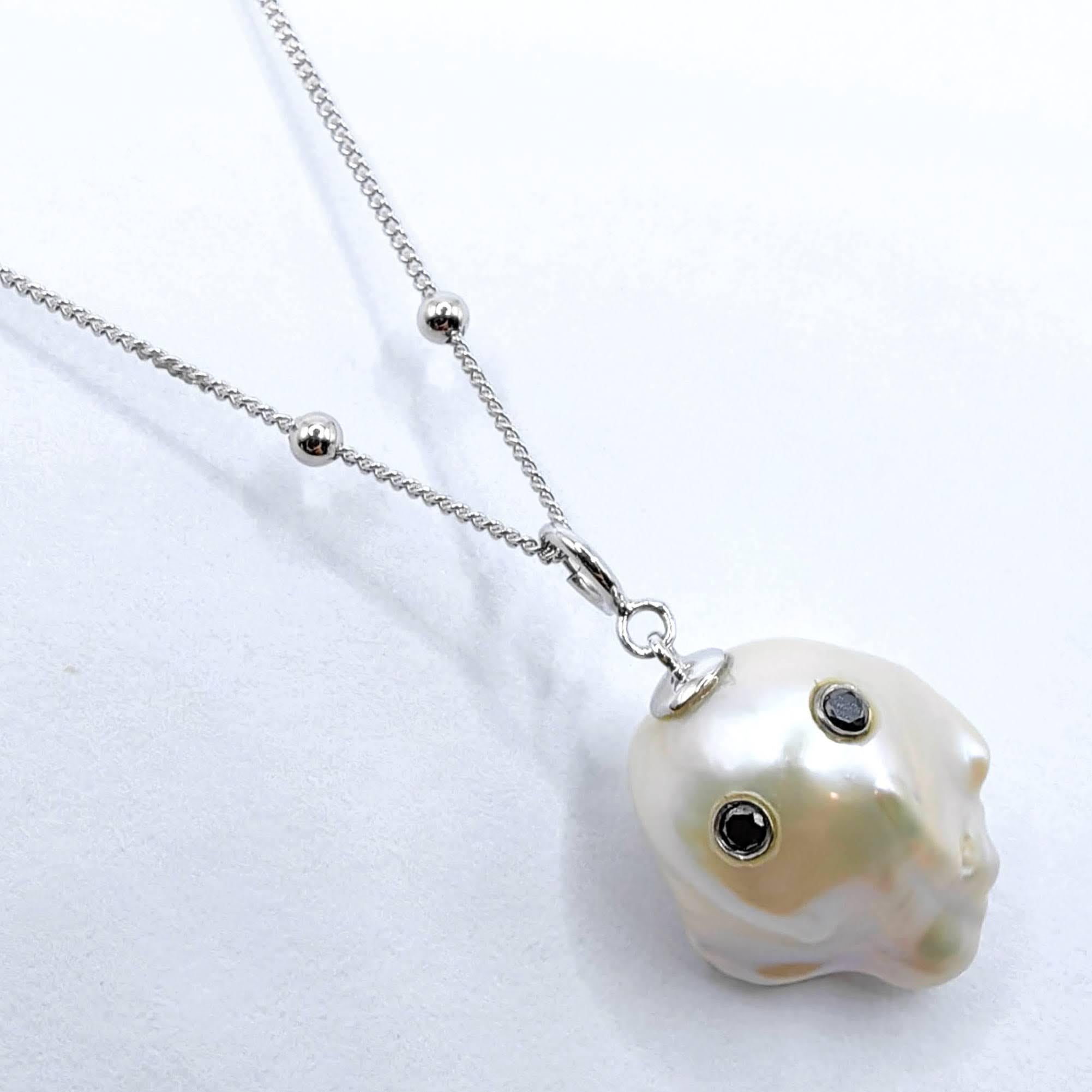 Unveil the enchanting Darling Phantom: a whimsical marvel featuring a Black Diamond accented Baroque Pearl set in 18K White Gold, evoking the spirit of a friendly ghost. This adorable piece, with a pendant length of approximately 1.05 inches