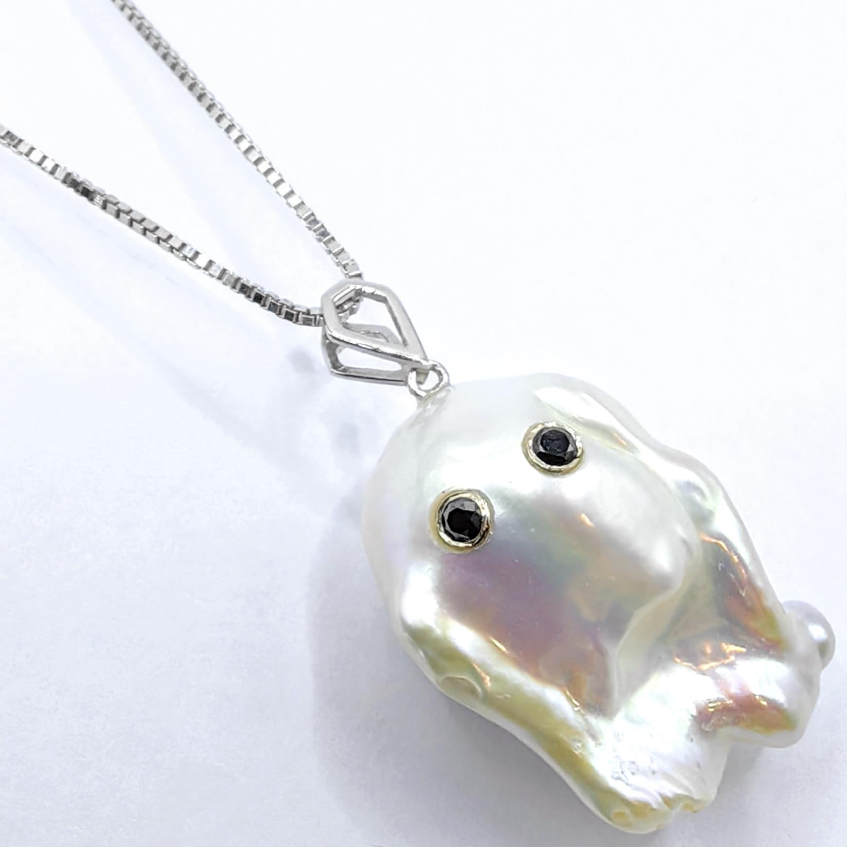 Expression envoûtante d'une élégance ludique, ce pendentif fantôme captivant en or blanc 18 carats transforme l'imagination fantaisiste en une luxueuse réalité. En son cœur se trouve une impressionnante perle de culture baroque d'eau douce de 26,11