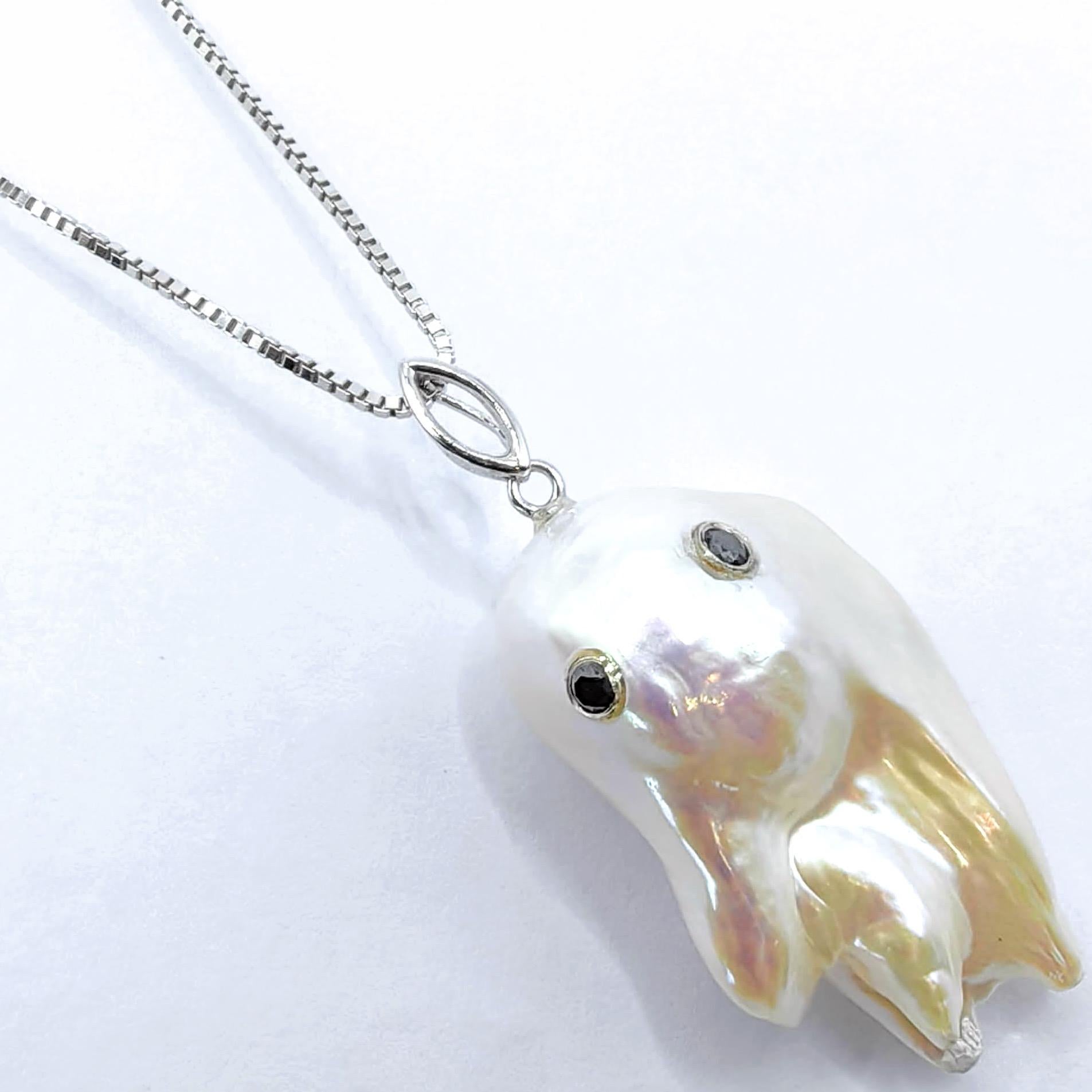 Incarnazione di una raffinatezza stravagante, questo incantevole ciondolo a forma di fantasma in oro bianco 18 carati trasforma l'immaginazione giocosa in arte da indossare. Al centro si trova una straordinaria perla d'acqua dolce coltivata barocca