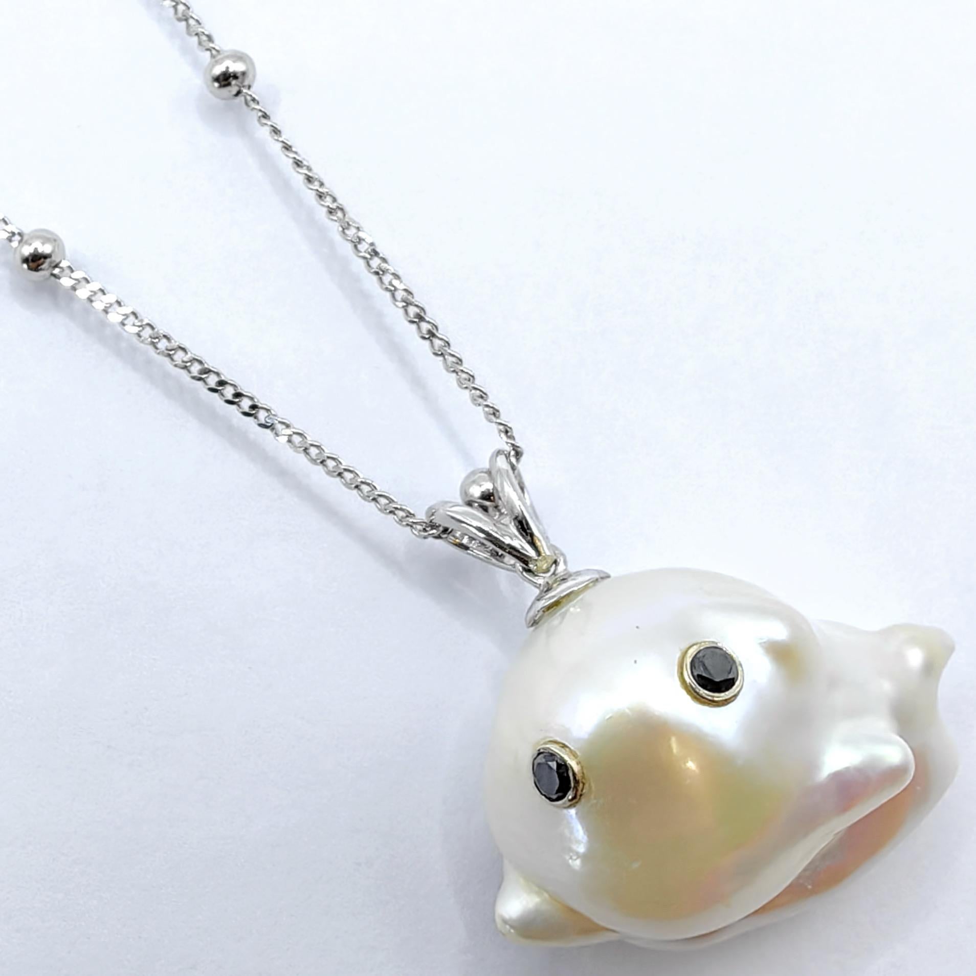 Expression délicieuse d'un luxe fantaisiste, ce charmant pendentif fantôme en or blanc 18 carats transforme l'imagination ludique en art raffiné. En son cœur repose une captivante perle de culture baroque d'eau douce de 26,86 carats, dont la forme