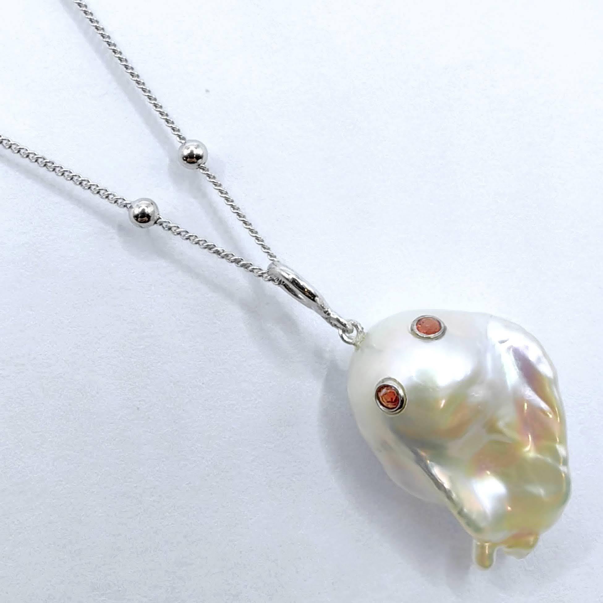 Découvrez l'envoûtant Darling Phantom : breloque et pendentif fantôme en saphir orange et perle en or blanc 18 carats, évoquant l'esprit d'un fantôme espiègle mais charmant. Cette pièce captivante, dont le pendentif mesure environ 3,04 cm, est