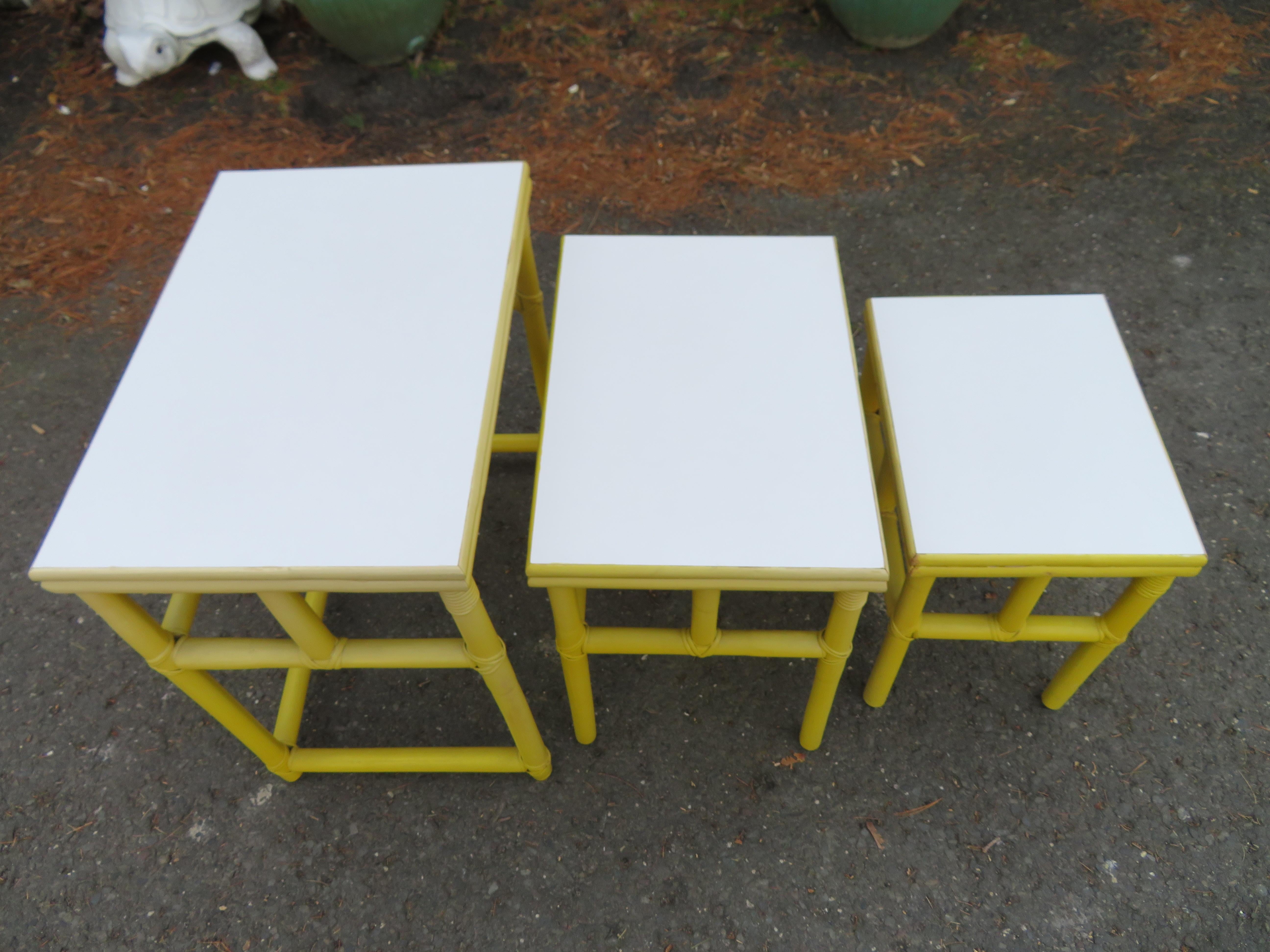 Darling set of 3 yellow rattan nesting tables with white Formica tops. We love these used in a covered porch or a Florida sunroom. The tops of each have a wonderful white Formica which is very durable and easy to care for. They measure 24.5