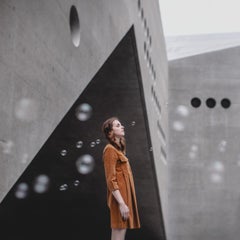 Framed color photograph w woman, bubbles, grey geometric architecture, orange