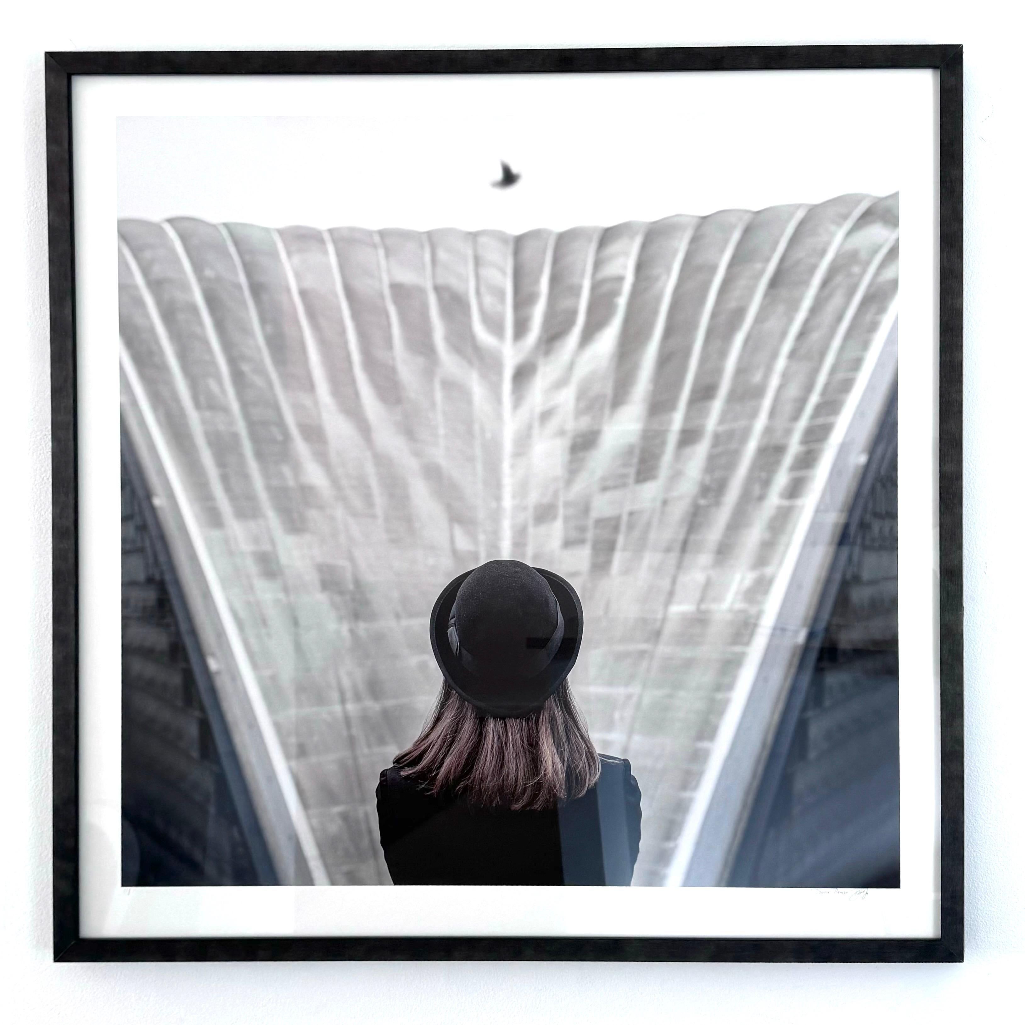 Photographie couleur encadrée d'une femme avec un chapeau noir de style Magritte, architecture grise en vente 1