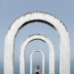 Framed Color Photograph: Woman at blue ocean w/ white arches looking at horizon