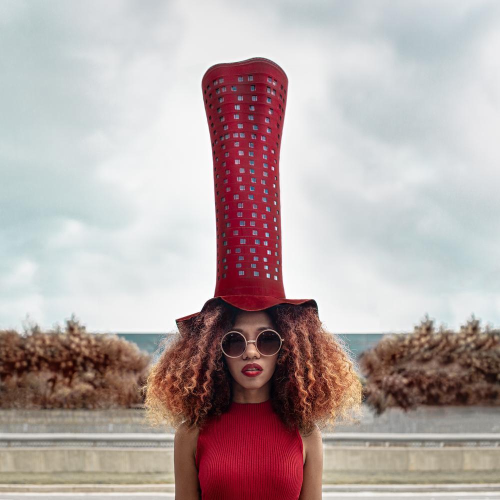 This beautifully vibrant red surreal portrait was shot in Barcelona. Dasha Pears cleverly arranges the composition so that the red building functions as the model's Dr. Seuss-like hat. This is a limited edition color photograph. Number 1 of 5 is