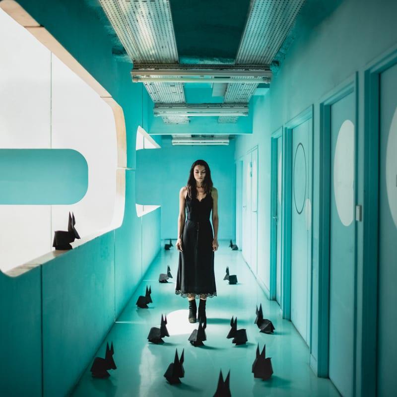 Gerahmte Farbfotografie Frau in türkisfarbener Architektur mit Origami-Bänken, gerahmt