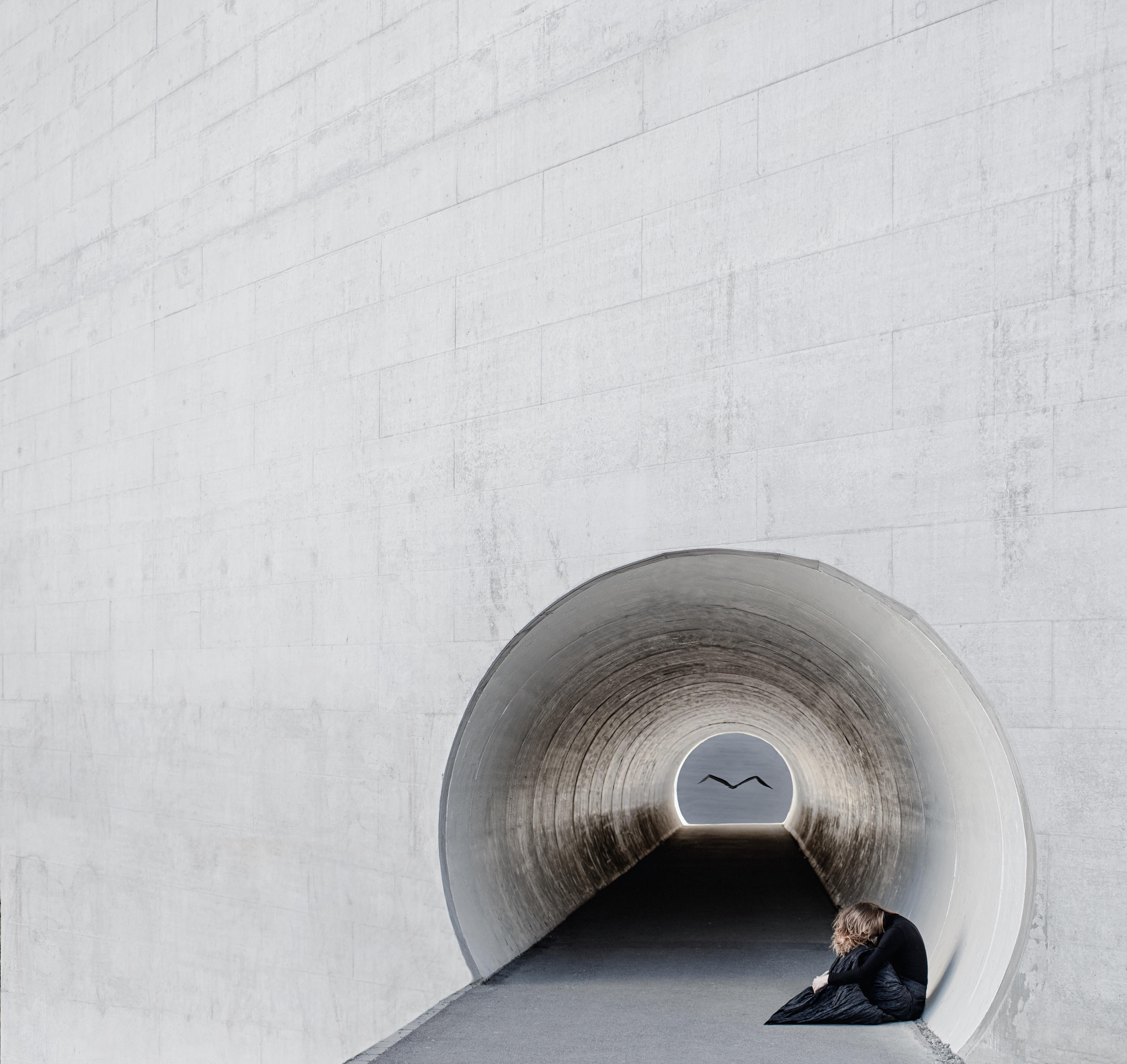There is always light at the end of a tunnel. Here, a woman struggles to find the light. An origami bird in the distance creates hope in this minimalist and clean composition. This is a limited edition color photograph. Number 1 of 18 is currently