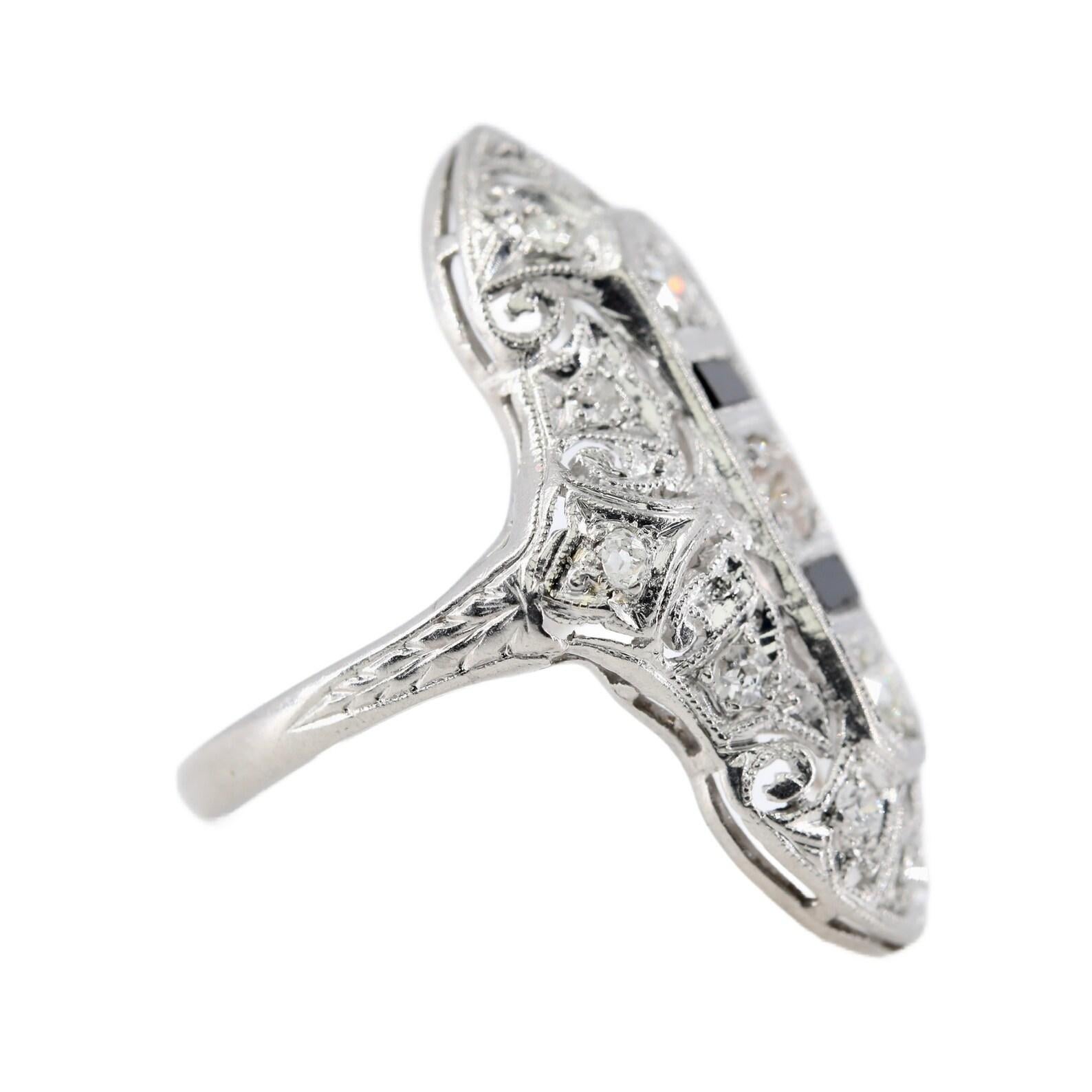 Bague de cocktail Art déco en diamant et onyx noir en platine. Au centre, un trio de diamants de taille européenne ancienne, compensé par de riches baguettes d'onyx noir. Elle est rehaussée de diamants pavés supplémentaires et complétée par des