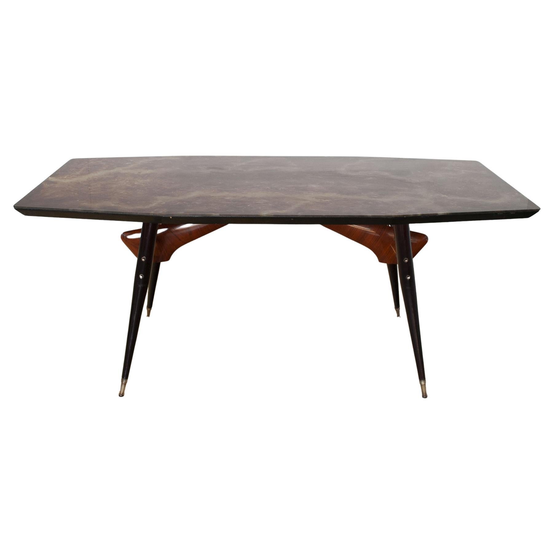 Table avec structure en bois laqué noir et cadre en noyer avec détails en laiton et plateau en verre avec effet écaille de tortue produite par Dassi dans les années 60.
Vittorio Dassi est un artiste italien d'après-guerre et contemporain né en