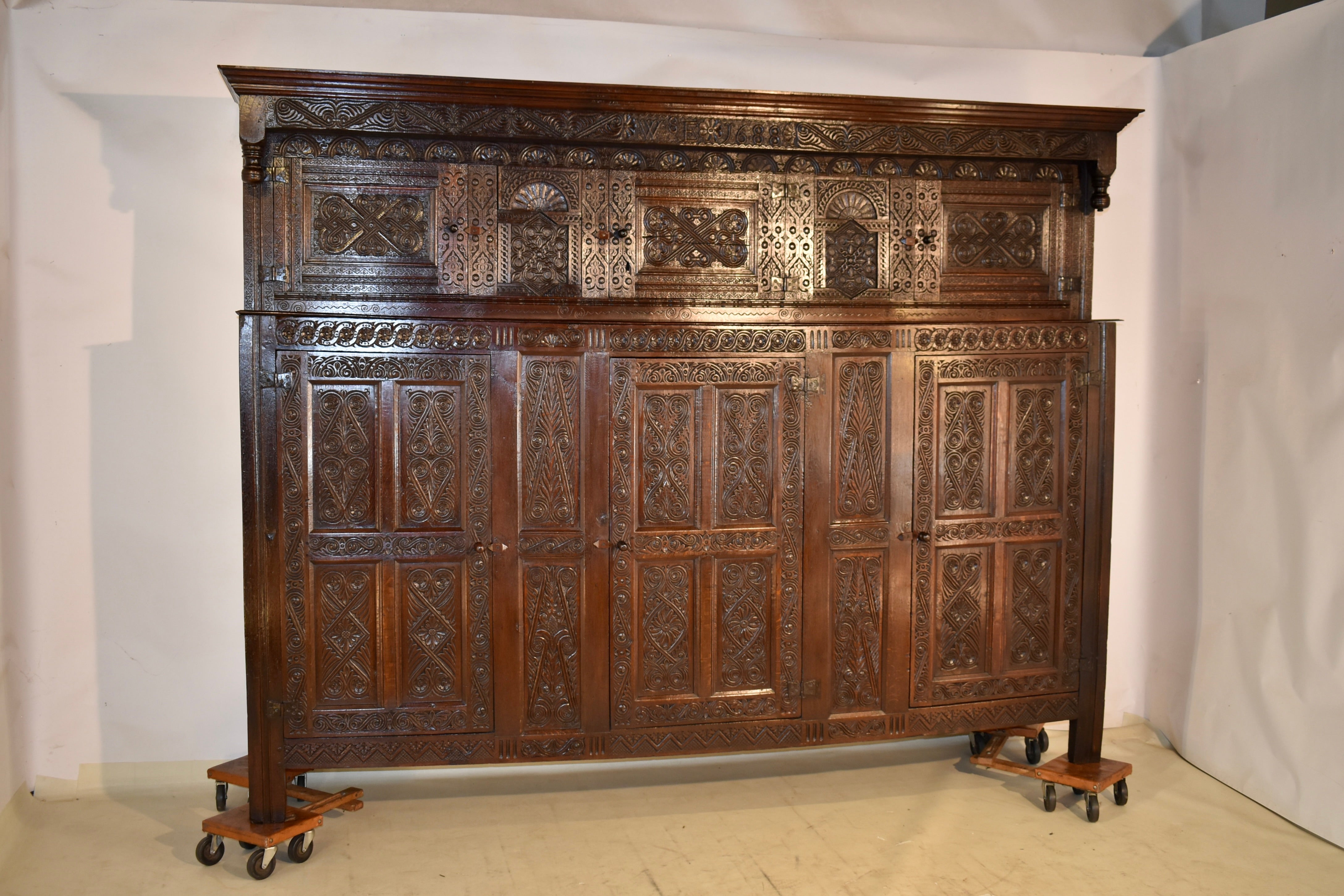 Dated 1688 James II period oak joined press cupboard from Northern England, probably Westmoreland and the Lake District area.  The top has a lovely crown molding, over five hand carved panels, with heavily carved interlace pattern on the three
