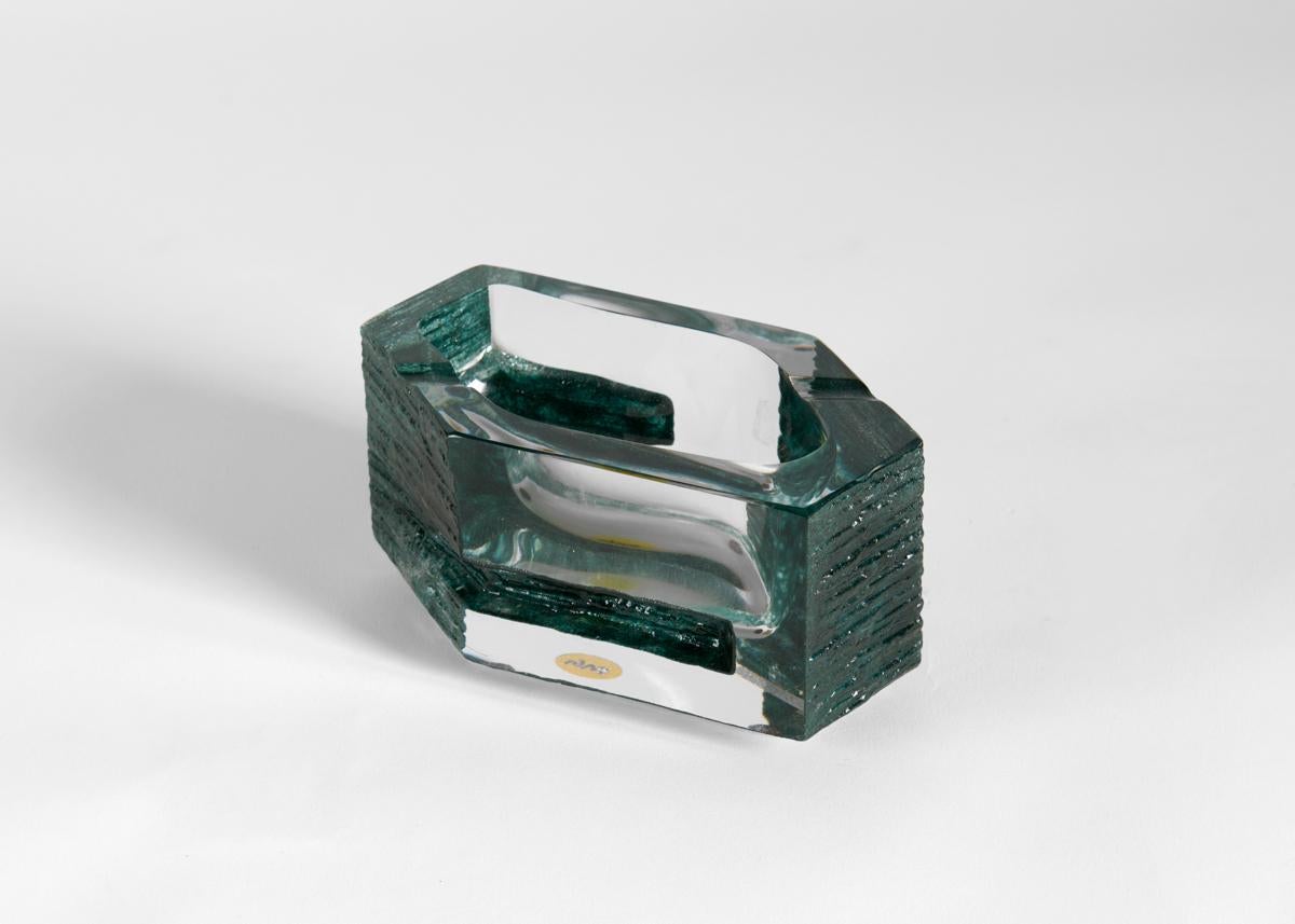 Originally intended as an ashtray, this heavy, blue crystal dish exemplifies the Brutalist aesthetic of sculptor César Baldaccini's collaboration with Daum with its combination of rough and smooth textures. 
Original label.