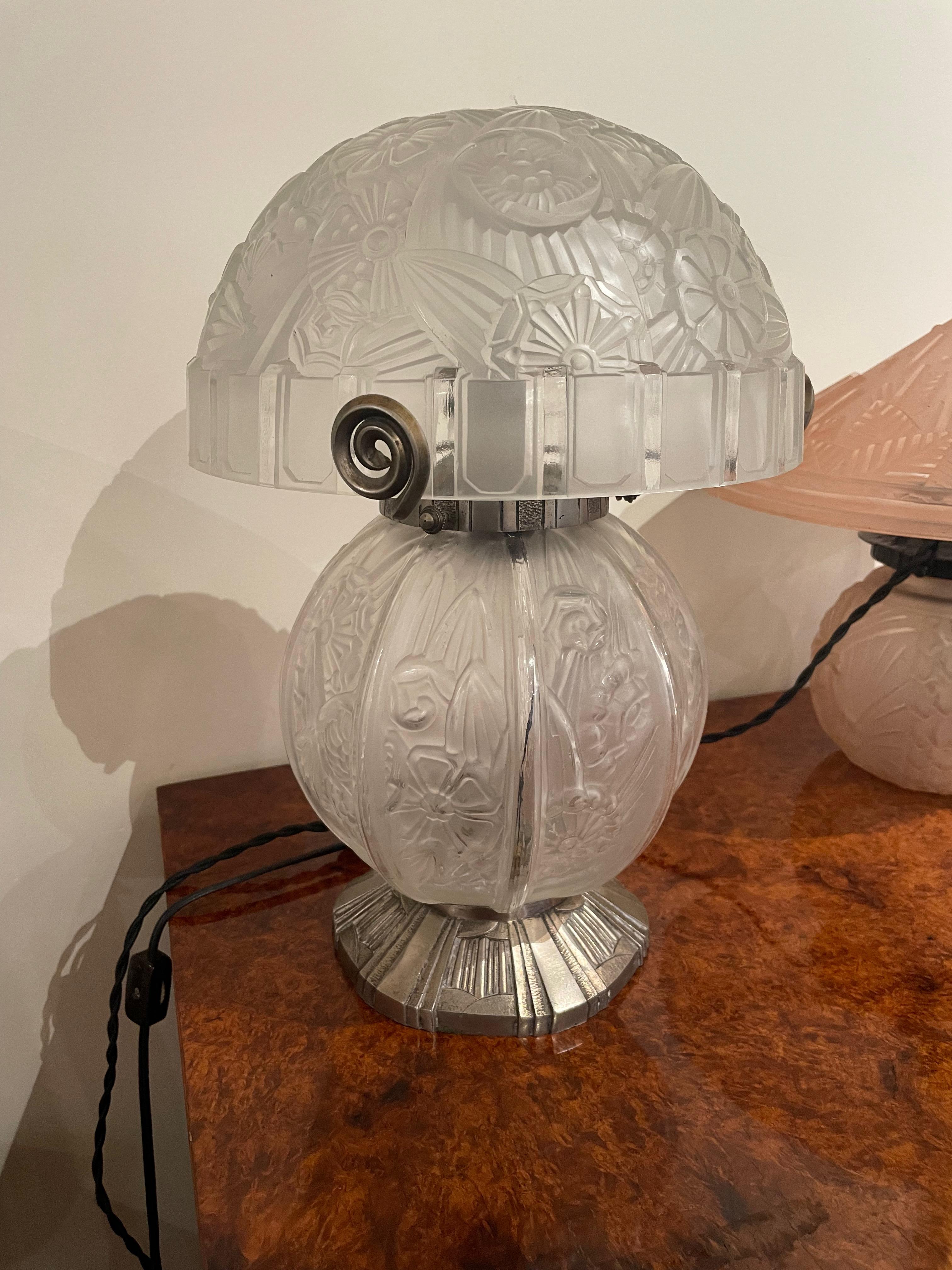 An Art Deco French double globe table lamp by Daum. This beautiful and unusual lamp is crafted in the “pate de verre” technique of thick glass heavily etched and carved in geometric, stylized floral pattern accented with handmade ironwork footing
