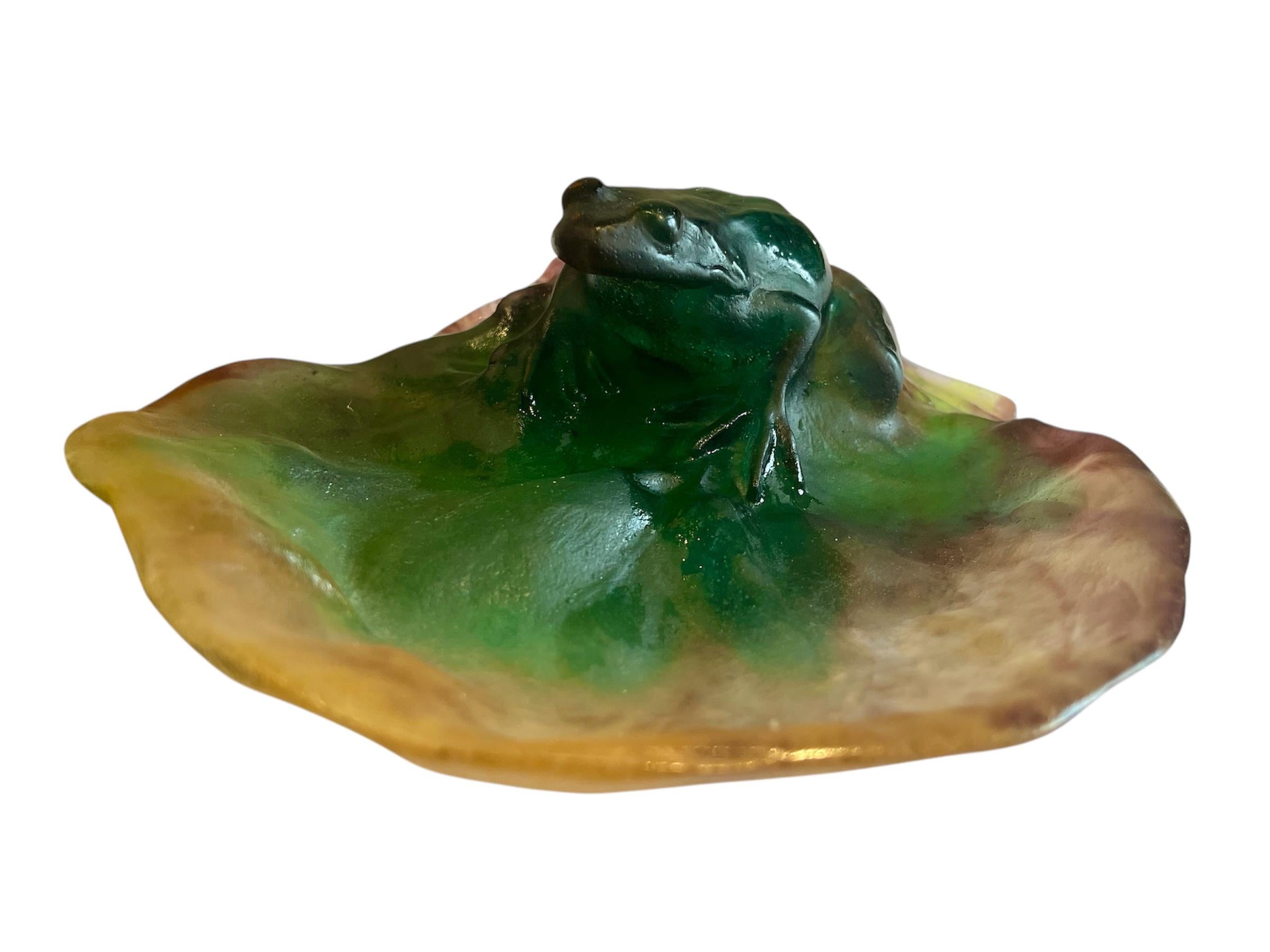 Glaspastendose mit der Darstellung eines Frosches auf einer Seerose. In den Farben grün, gelb und lila. Unter dem Sockel signiert 