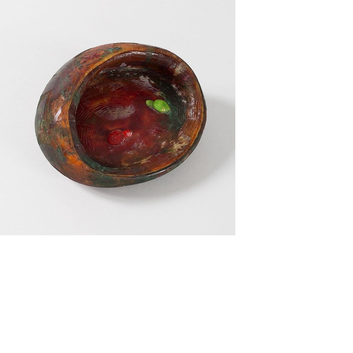 A French Art Nouveau wheel carved glass vide poche with elements of silver foil by Daum. The exterior of the vide poche has a red dragonfly floating over carved red and green leaves, with an orange background. The interior has one red and one green