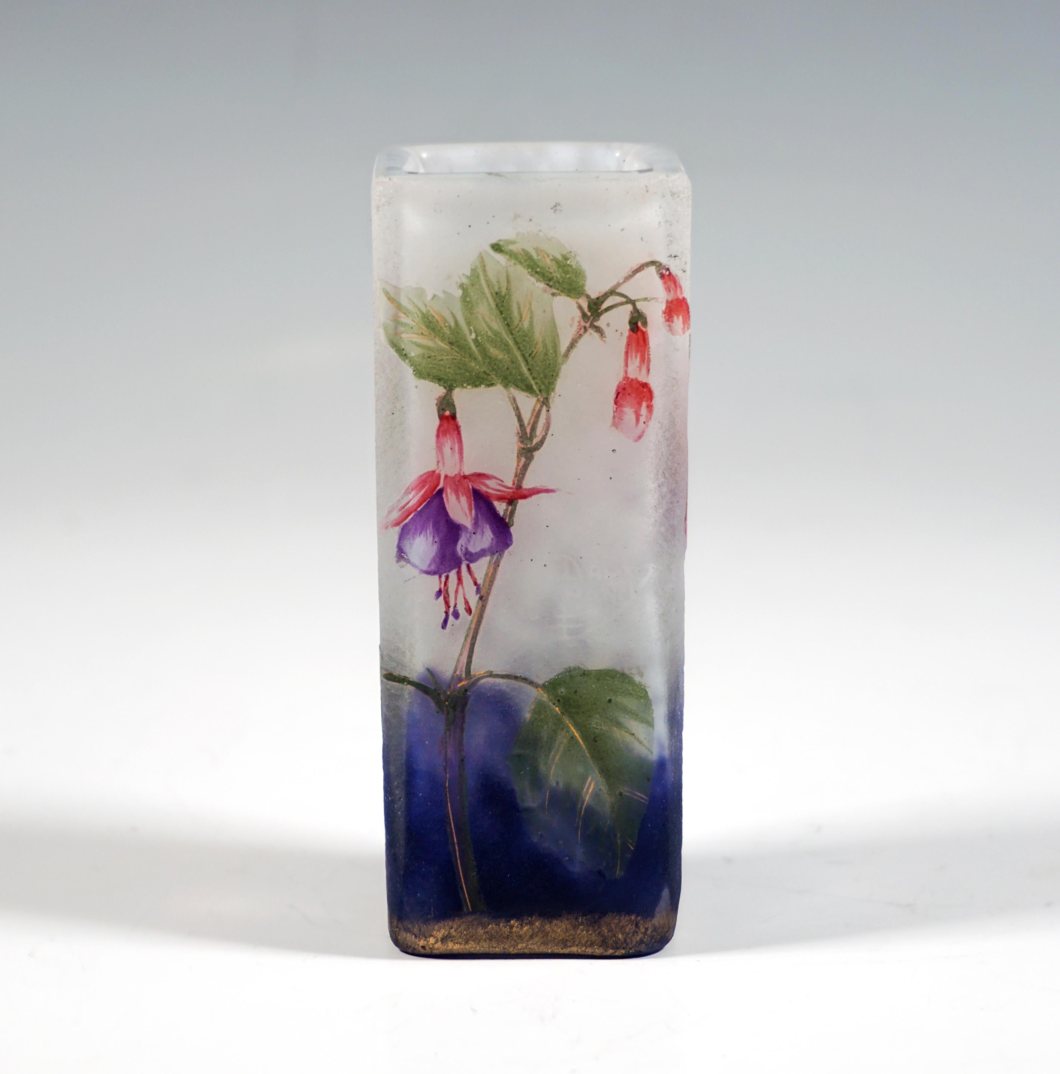 Un travail d'orfèvre sur le verre de l'Art nouveau français :
Vase angulaire de plan carré, verre incolore à blanc feuilleté, dans la zone du pied avec des fusions de poudre bleu cobalt, gravure et en émail coloré peint décor fuchsia avec élévation