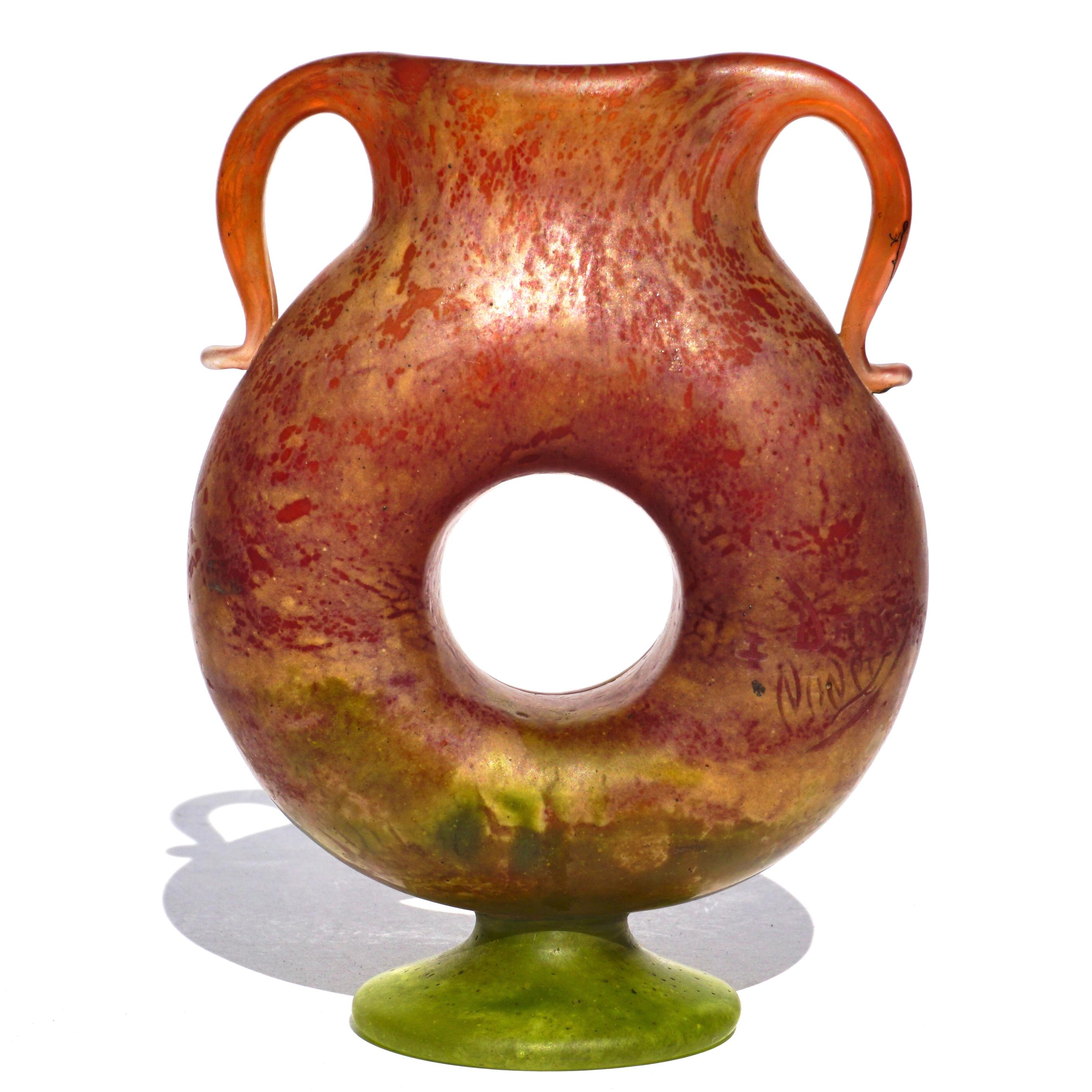 Daum Nancy Jugendstil Vase mit Fuß und appliziertem Henkel. Eine sehr seltene donutförmige Vase mit schönen applizierten Henkeln. Von Rot über Rosa und Creme bis hin zu Grün.

Höhe: 5 Zoll
Breite: 3,75 Zoll

Zustand: Neuwertig

Signiert Daum Nancy