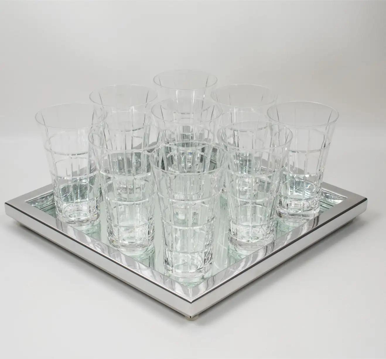 Daum Nancy France hand-crafted this elegant crystal barware serving set in the 1970s. The bar set features nine tulip tumbler glasses with deep geometric etching. Each item is labeled with the 