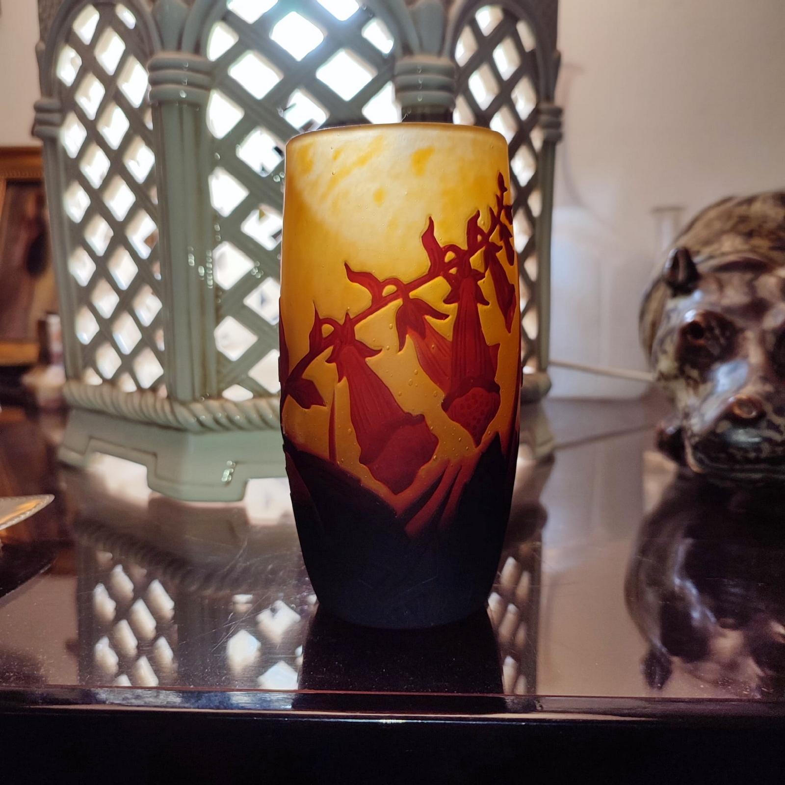Vase en verre multicouche, en technique de camée. Forme cylindrique en orange, rouge et brun tachetés, vers 1910.
Le décor de fleurs et de feuilles est gravé en réserve et repris à la roue, de couleur rouge cramoisi sur un fond jaune orangé moucheté