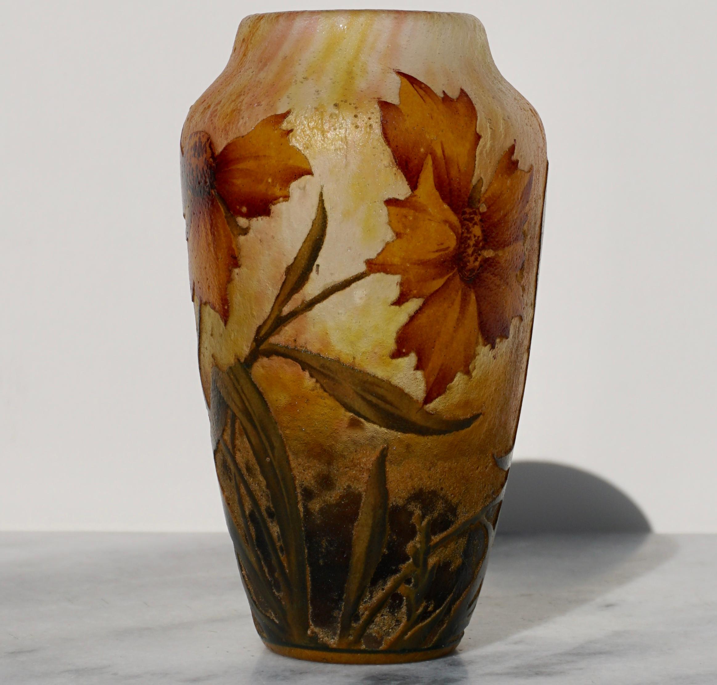 Daum Nancy French enameled cameo glass vase, circa 1910. Depicting six beautiful orange and red flowers from budding to full bloom stages with leaves and grasses. Thick wheel carved and acid etched with enameling in greens, blues, oranges and reds.