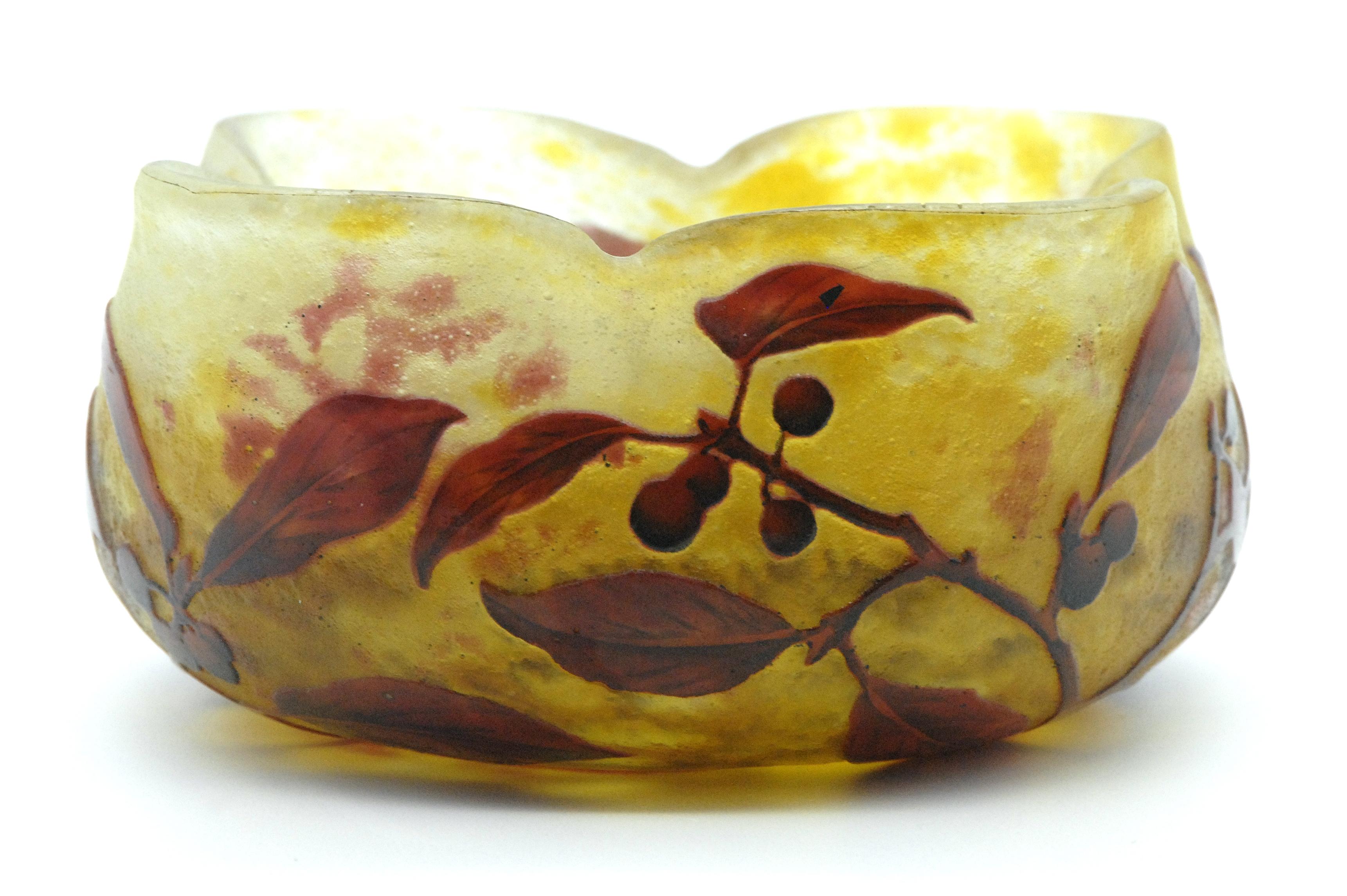 Leaves and berries trail on this rare cameo art glass bowl by the renowned French glassmaking firm of Daum, Nancy. The graceful vessel features a wavy-edged rim and orange/red leaves and berries trailing upon a sunset background of yellow and amber.