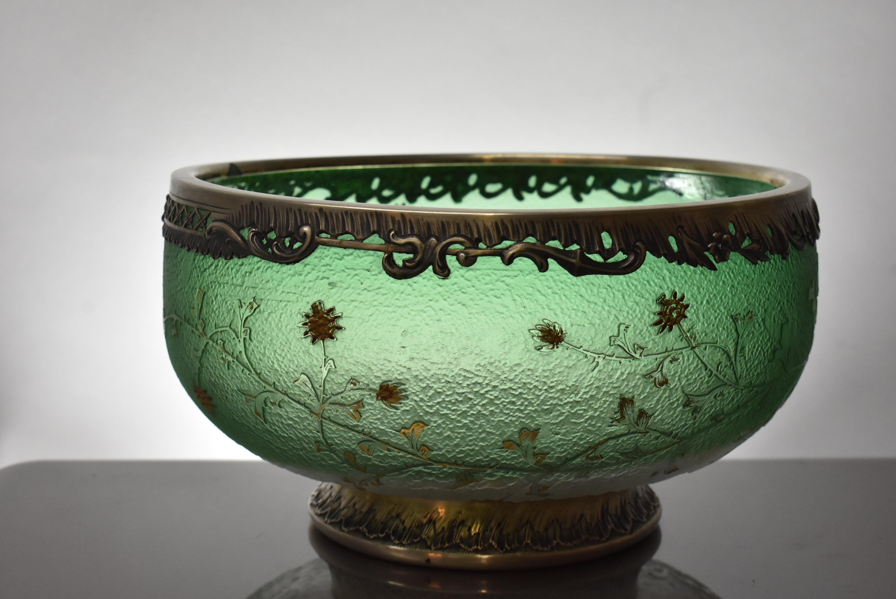 Cuenco grande con pie y forma bulbosa de cristal camafeo verde de Daum Nancy. Borde decorativo y embellecedor inferior de plata de ley. El diseño del camafeo de la espalda representa espirales de cardos con finas ramas espinosas. Las flores doradas