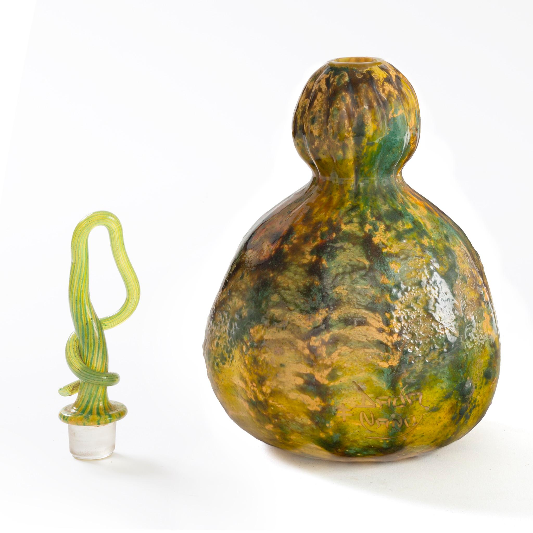 Questo squisito flacone Daum Nancy 'Coloquinte' combina un'incredibile varietà di tecniche. Il corpo del vaso utilizza la tecnica dell'intercalaire, con la quale il vetro in polvere verde, giallo ocra e umbero bruciato è stato cosparso tra gli