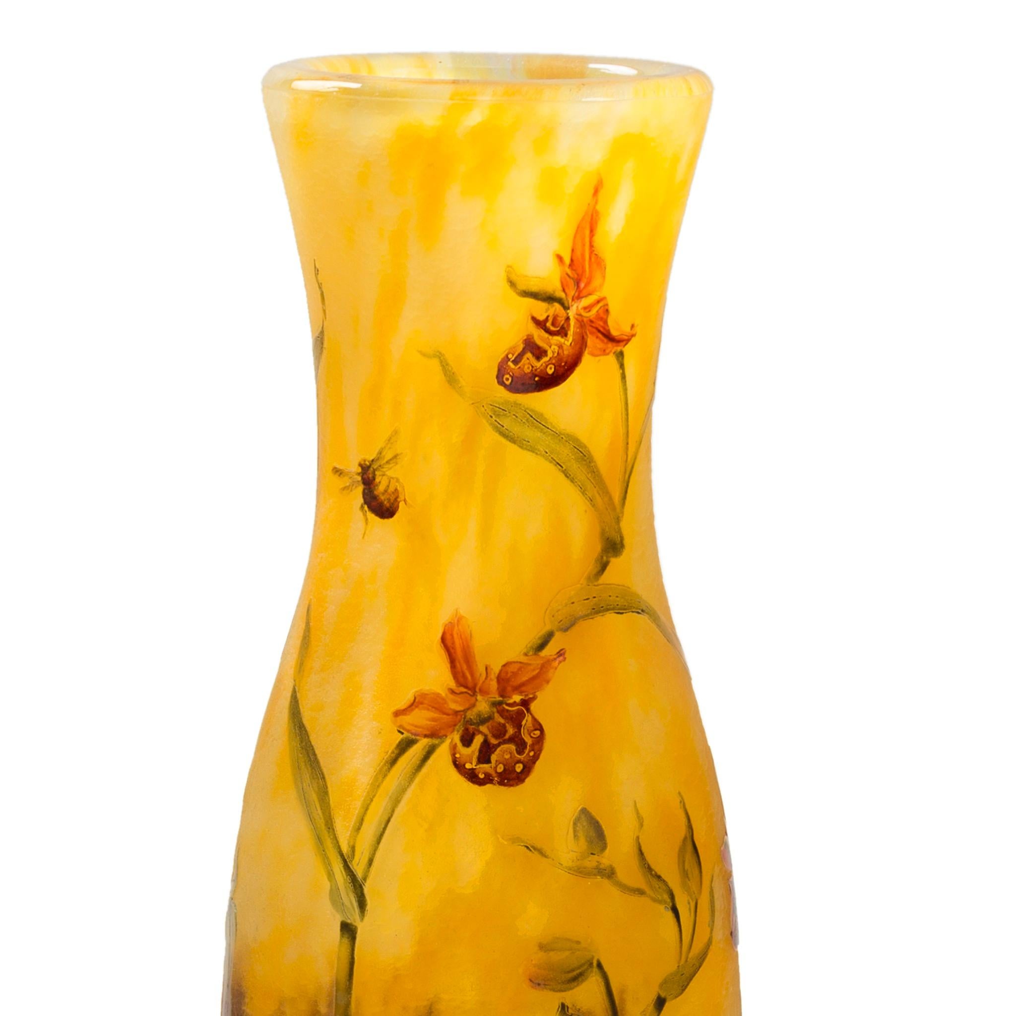 Este jarrón francés Art Nouveau de cristal esmaltado y grabado de Daum Nancy es una escena brillante está dominada por dos planos de cristal moteado, amarillo dorado sobre morado intenso, que juntos crean un paisaje. El jarrón está decorado con