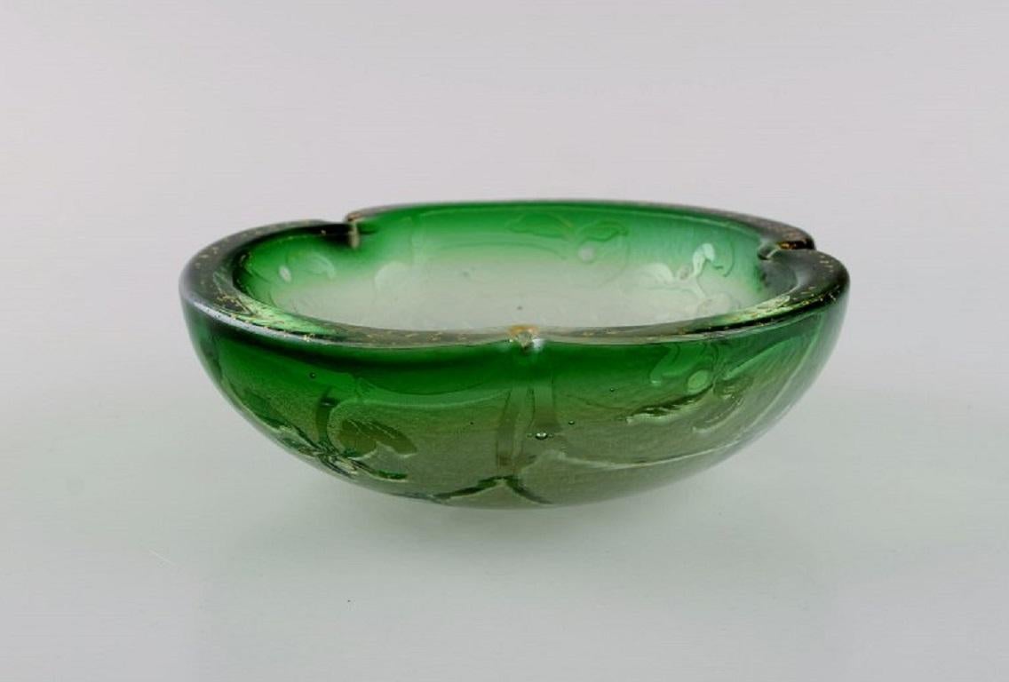 Daum Nancy, France. Art Nouveau bowl in green mouth-blown art glass. 
Embossed flowers and hand-painted gold decoration. Approx. 1900.
Measures: 15 x 5 cm.
In excellent condition.
Signed.