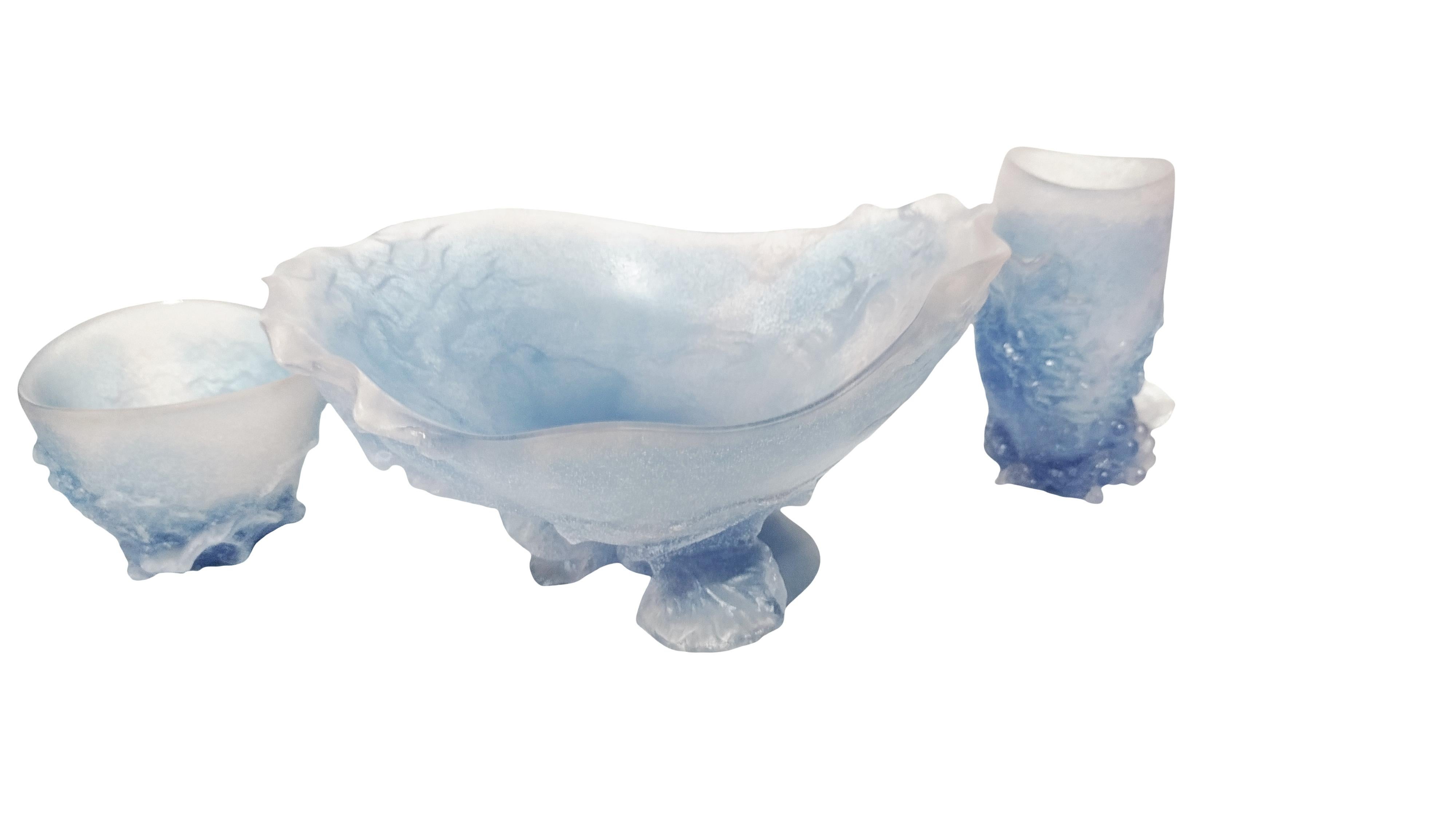 Dieses elegante Set, bestehend aus einer Obstschale und zwei Vasen, wird von der renommierten französischen Glasmanufaktur Daum-Nanci hergestellt. Die aus Glaspaste gefertigten Stücke weisen zarte Blau- und Rosatöne auf, die durch fein ausgeführte