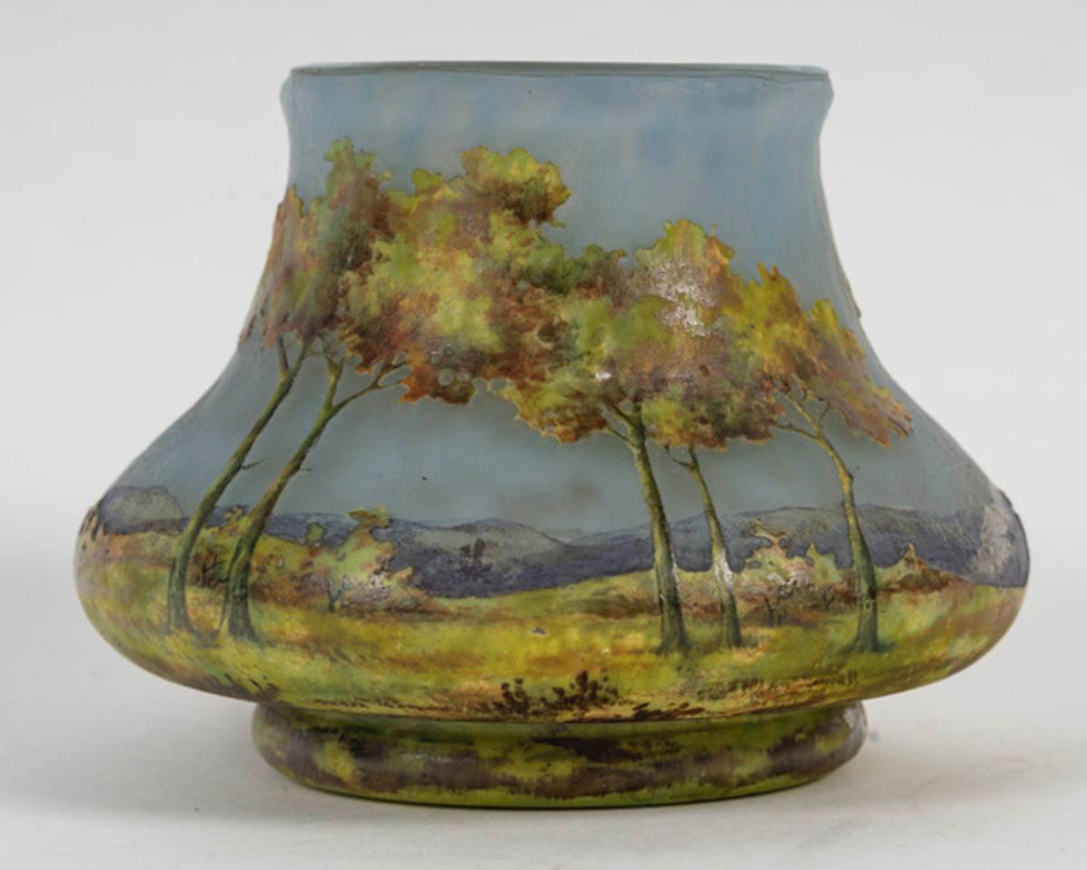 Small vase with flattened body in marbled glass
multilayer acid-etched with polychrome decoration of a wooded meadow in a mountainous background reworked with a brush. 

Signed with the Lorraine cross and the initials AP of the decorator. 

H. 7