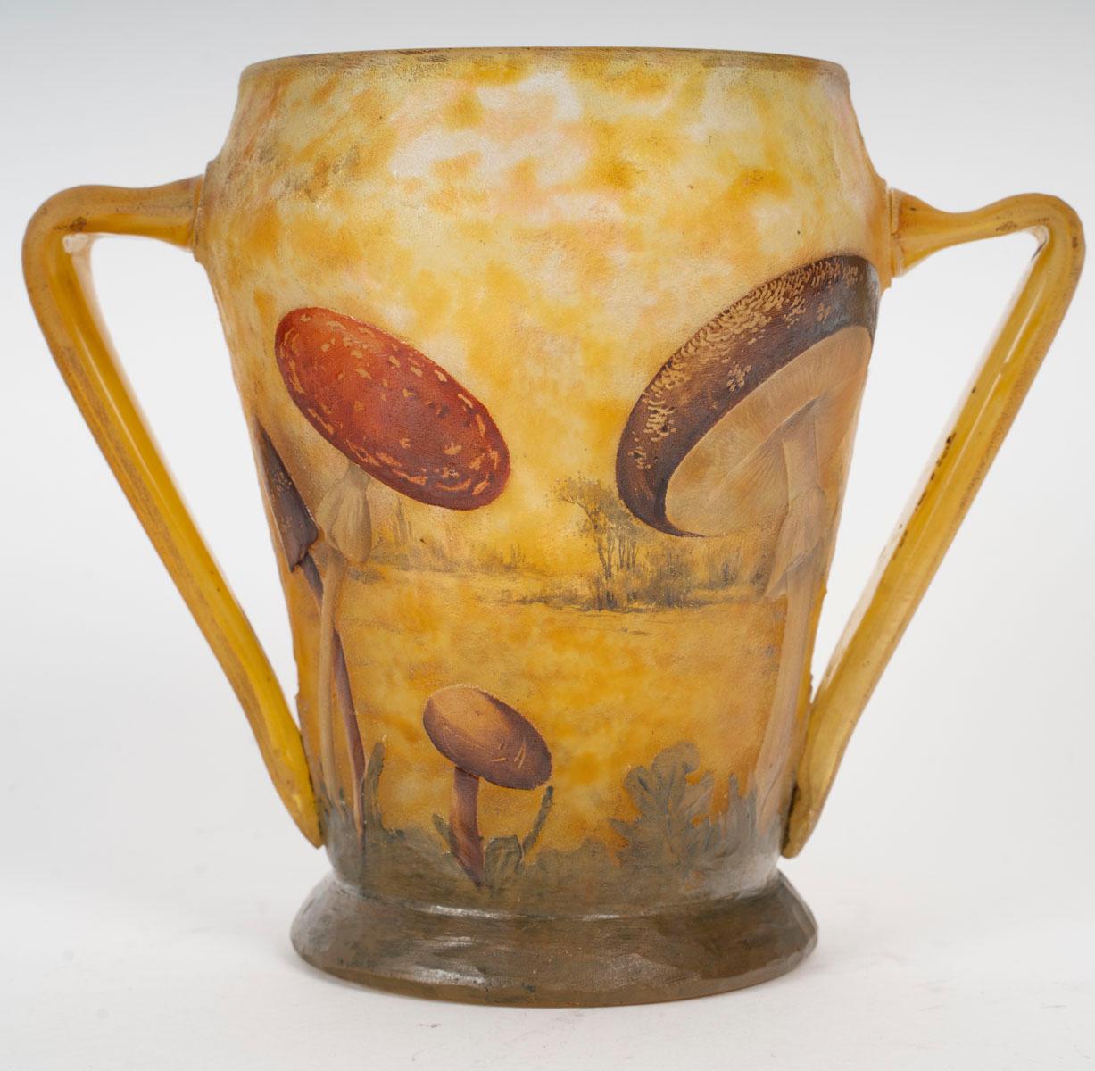 Rare vase by the Daum Nancy house decorated with wild mushrooms in acid- and wheel-cleared enameled glass, with an interlayer decoration of a wooded landscape in the background. It is decorated with two hot-applied handles and rests on a base
