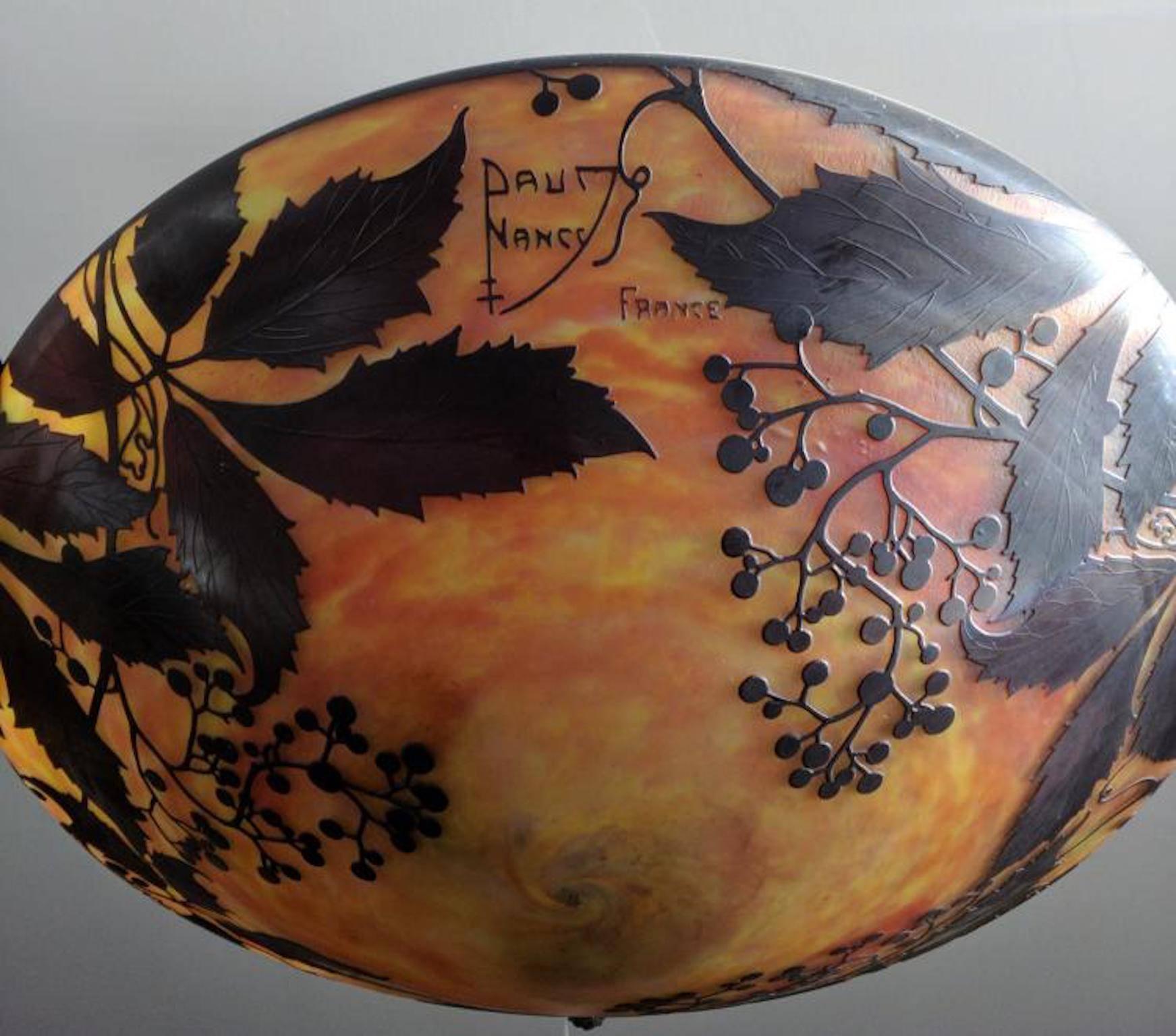 The glass bowl hanging on three struts, the surface etched with lush wild vines decor, the frosted glass with cloudy powder merges in yellow and purple.
Signed Daum Nancy France.