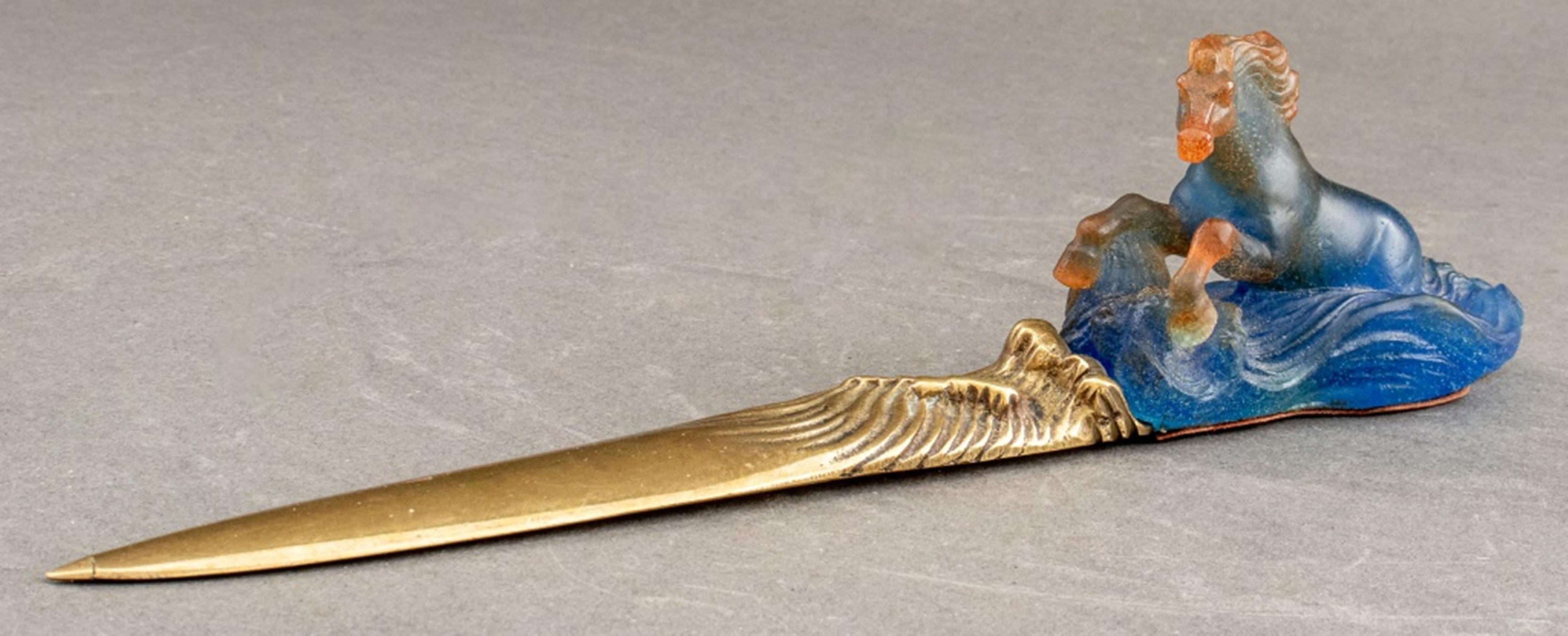 Daum letter knife, the blue and orange pate de verre glass handle in the form of a merhorse emerging from the sea, the blade of gilt bronze.

Dimensions: 11.25
