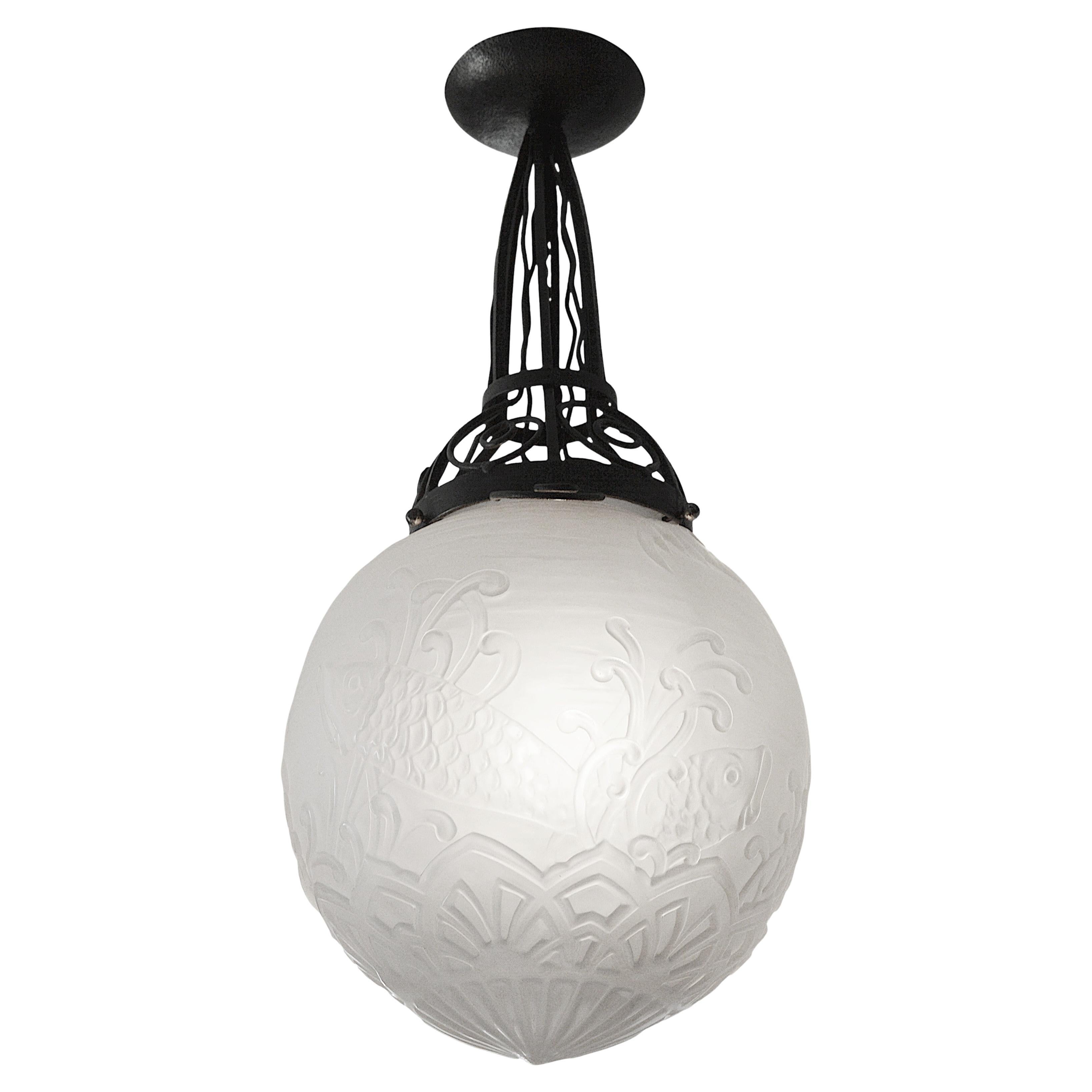 This exceptional Art Deco chandelier, designed by Pierre D'Avesn for Daum (Croismare, Nancy) in the 1920s, features a magnificent decorative motif depicting two fish swimming amid delicate seaweed. The thick, molded, satin-finished glass shade is a