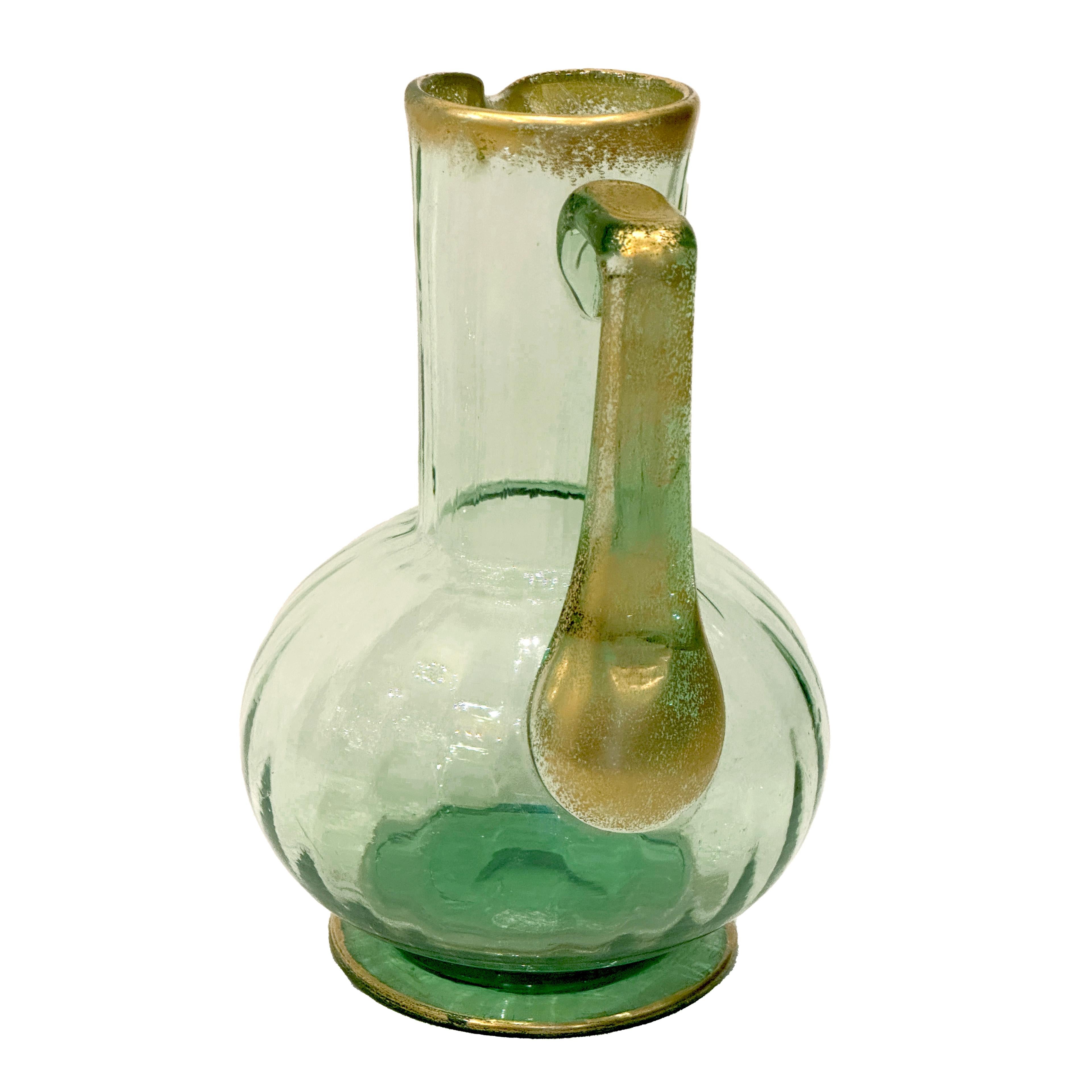Questa brocca per acqua in vetro soffiato color verde smeraldo mette in mostra l'eccezionale maestria della manifattura Daum di Nancy, circa 1900. Il corpo sottilmente scanalato aggiunge un senso di movimento e consistenza, mentre gli eleganti