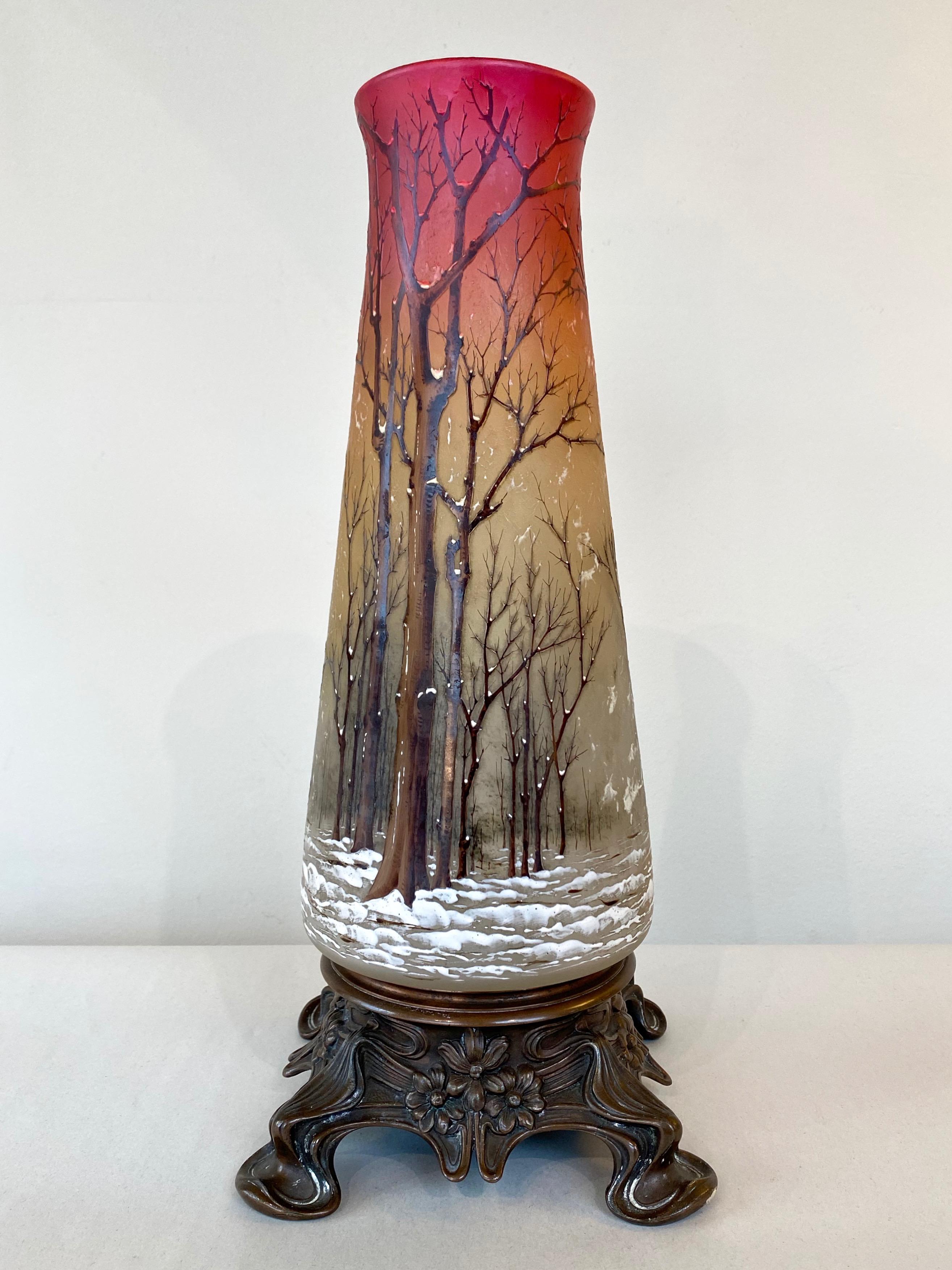 A very striking and uncommon circa 1900 Daum “Winter Landscape Scene” enameled cameo glass vase or lamp body on elegant Art Nouveau bronze base. Coloration, form, and base unlike any other Daum Nancy piece with the same motif of which we’re aware,