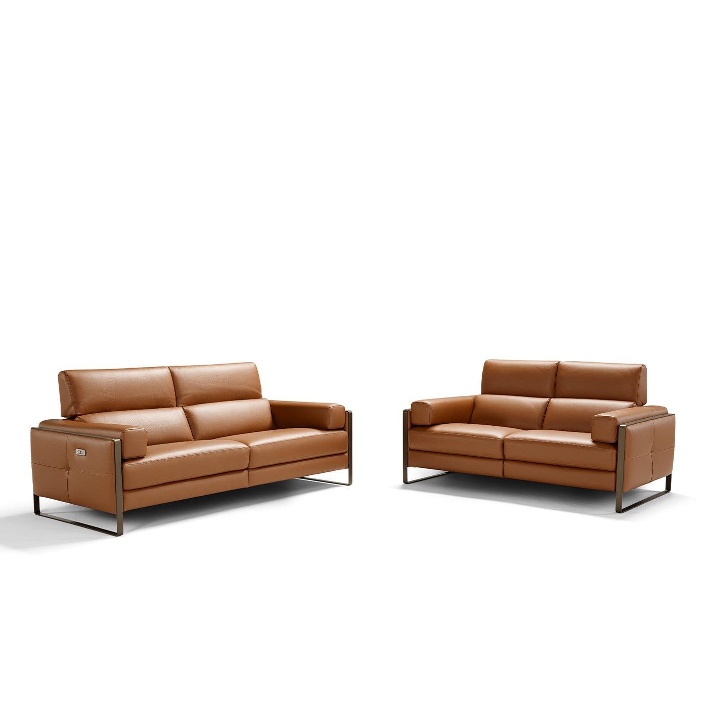 Synthesizing comfort and style, this two-seater sofa flaunts a fine leather upholstery in a warm shade of cognac brown. Its modular design consists of two seats linked by joints, whose headrests can be inclined manually or adjusted in height by
