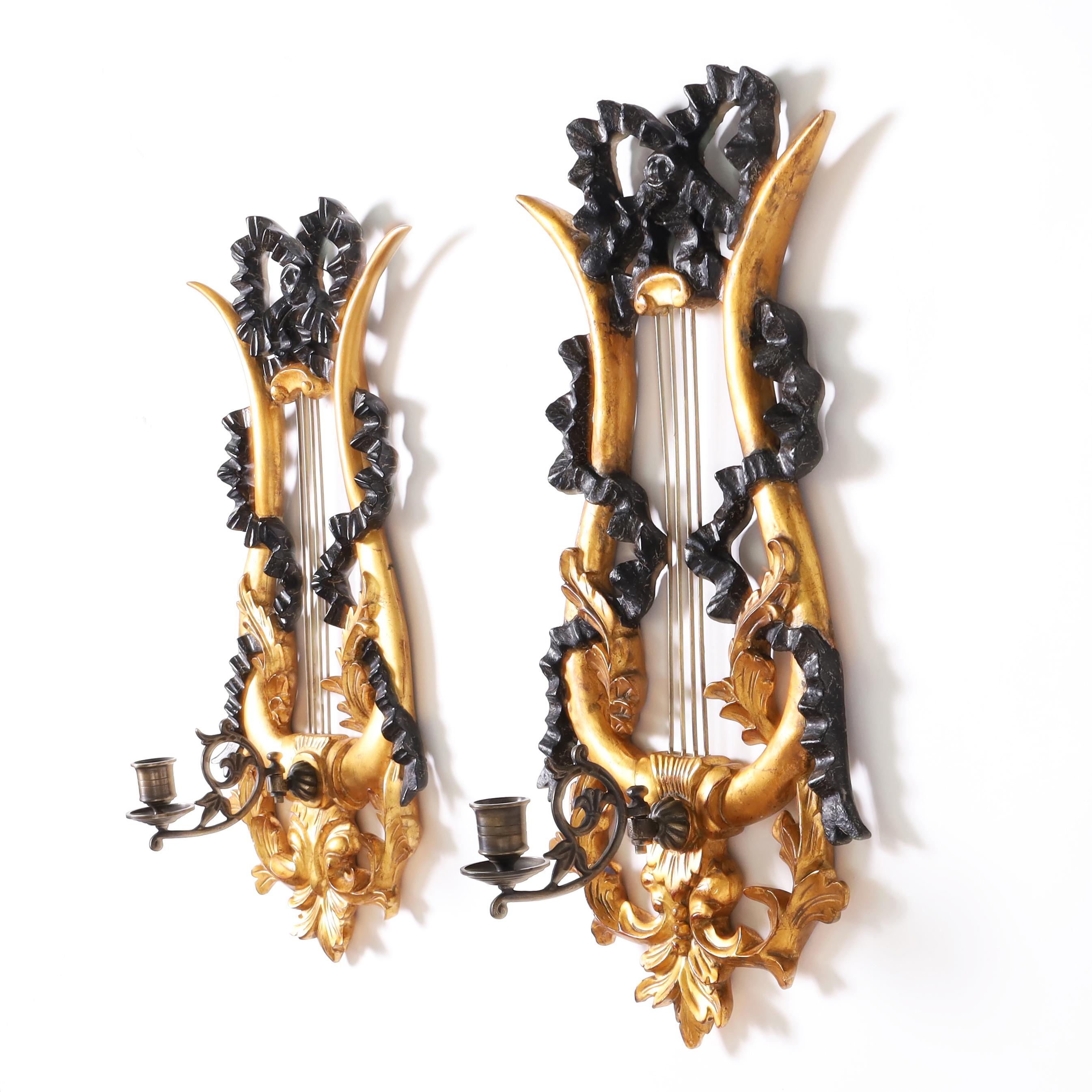 Coppia di appliques a una luce in pacchi dorati scolpiti a mano in una classica forma a lira con nastri e foglie d'acanto, con coppe per candele in ottone brunito su una staffa floreale. Etichettata sul retro Dauphine Harrison & Gil.