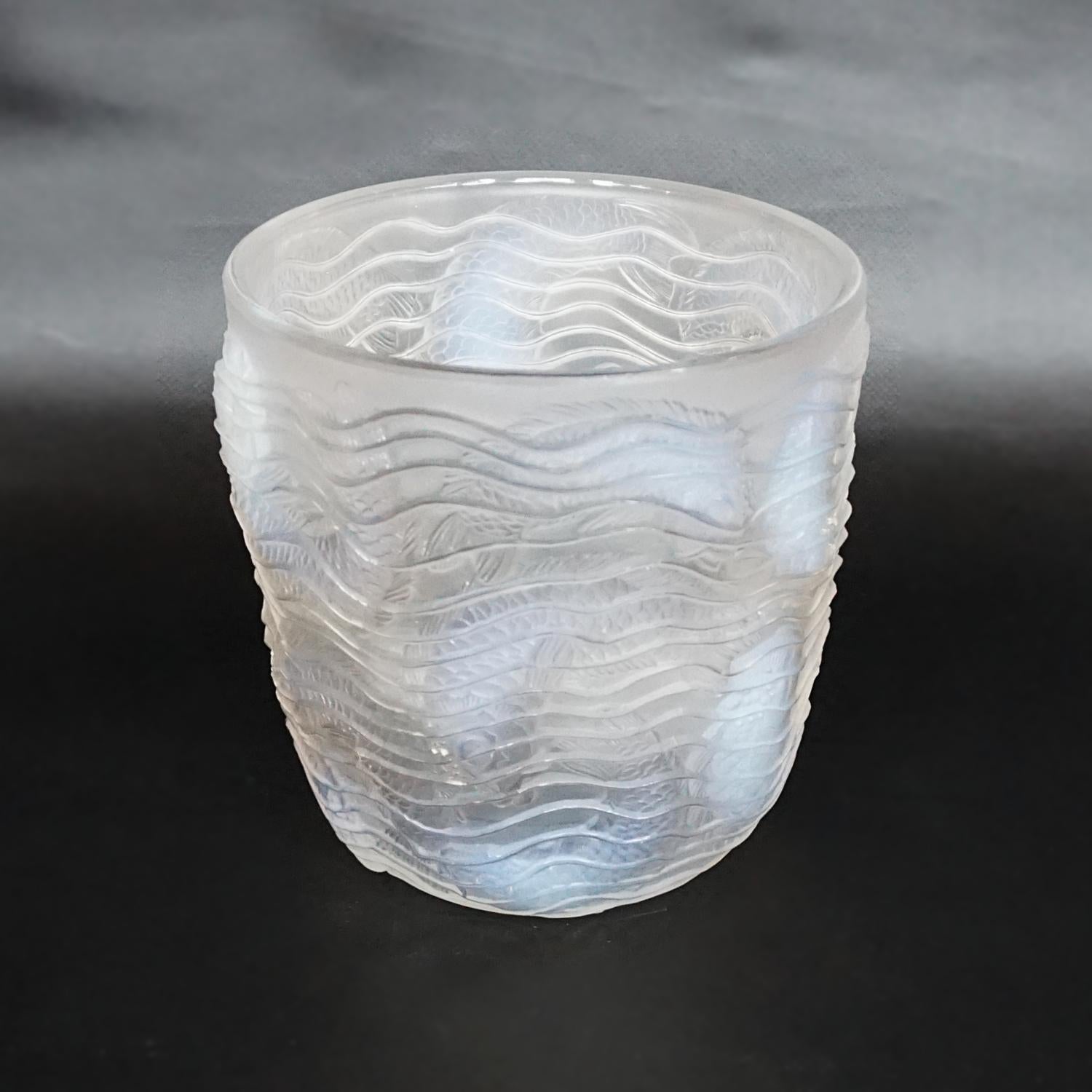 Dauphins, an Art Deco opalescent glass vase by René Lalique (1860-1945). Raised, swirling pattern with graduated blue opalescent swimming fish. Etched 'R Lalique France' to underneath.

Literature: Marcilhac Catalogue Raisonné de L’Oeuvre de Verre