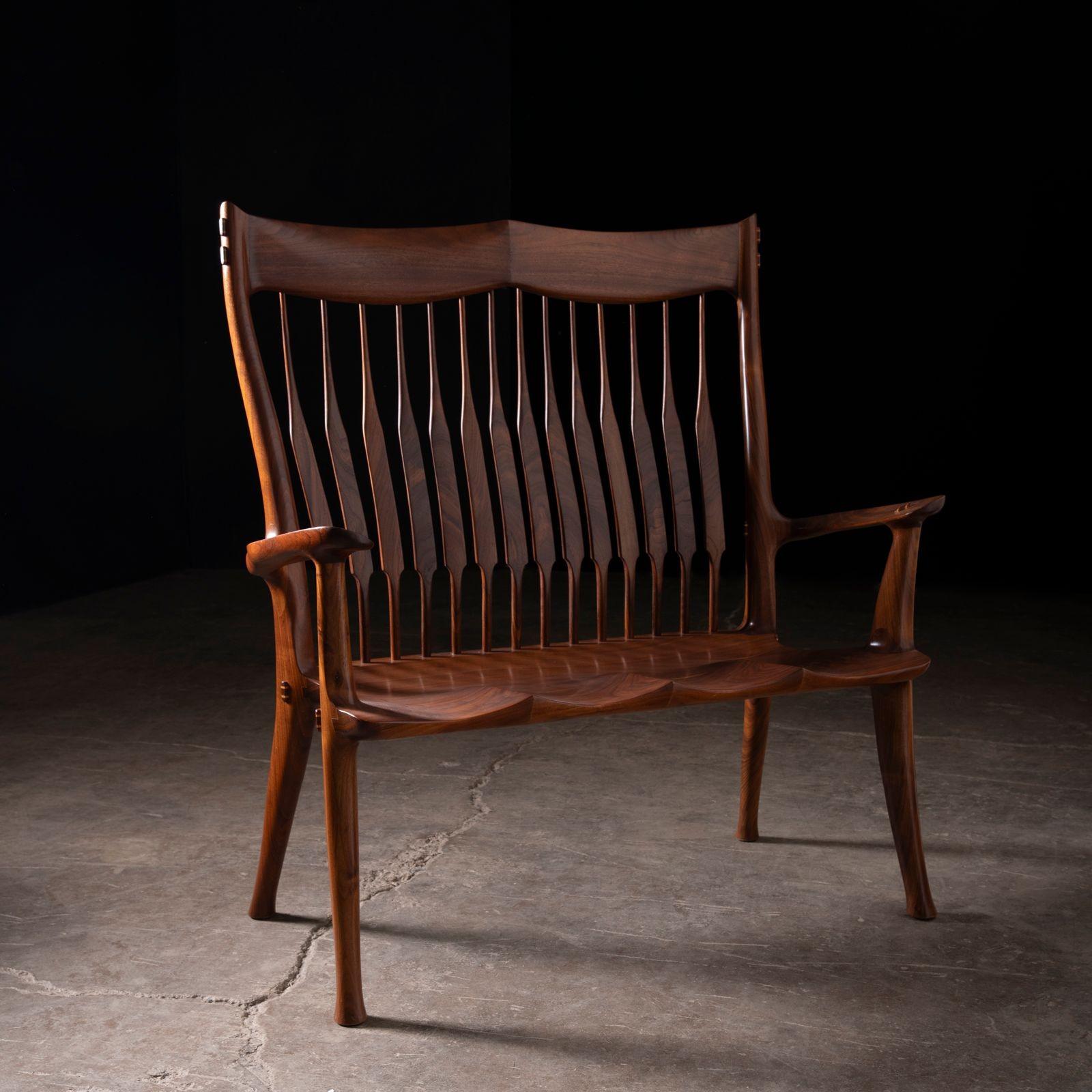 A masterfully carved studio-crafted two-seater bench in richly figured claro black walnut, designed and fabricated by Dave Hentzel—an accomplished American craftsman. Inspired by the legendary work of Sam Maloof, this bench reflects the spirit of